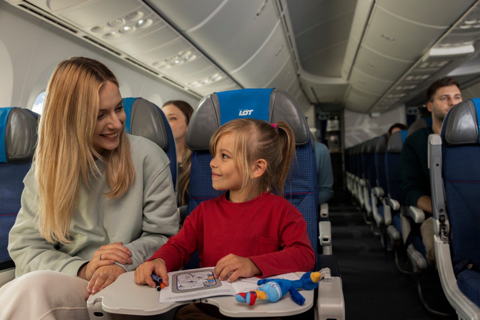 A child aboard the Dreamliner is busy with a coloring book, a Lotek plushie lies next to it