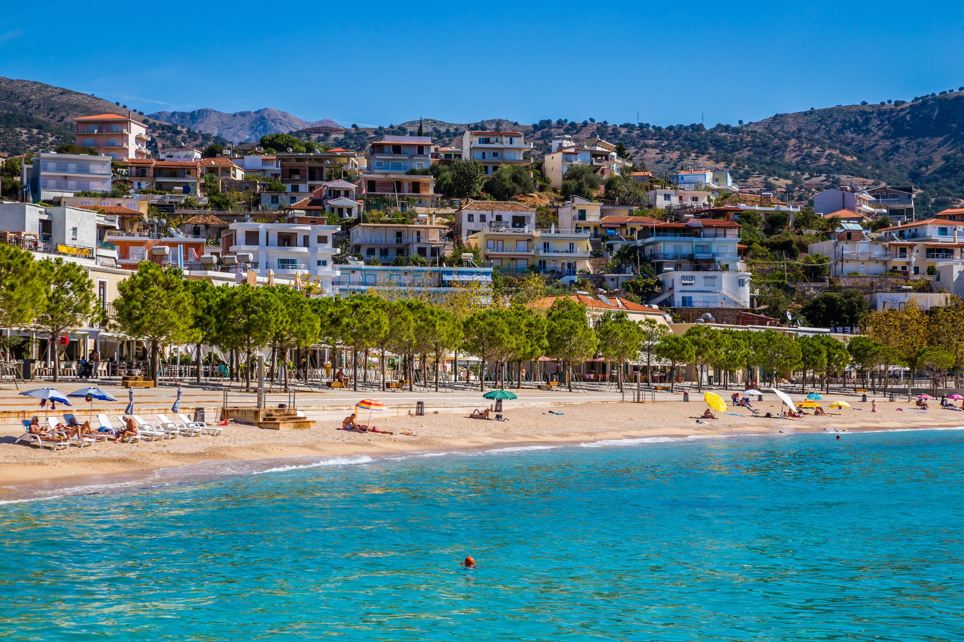 Plaża w Himarze, Albania. Błękitne morze, piasek i góry w tle.