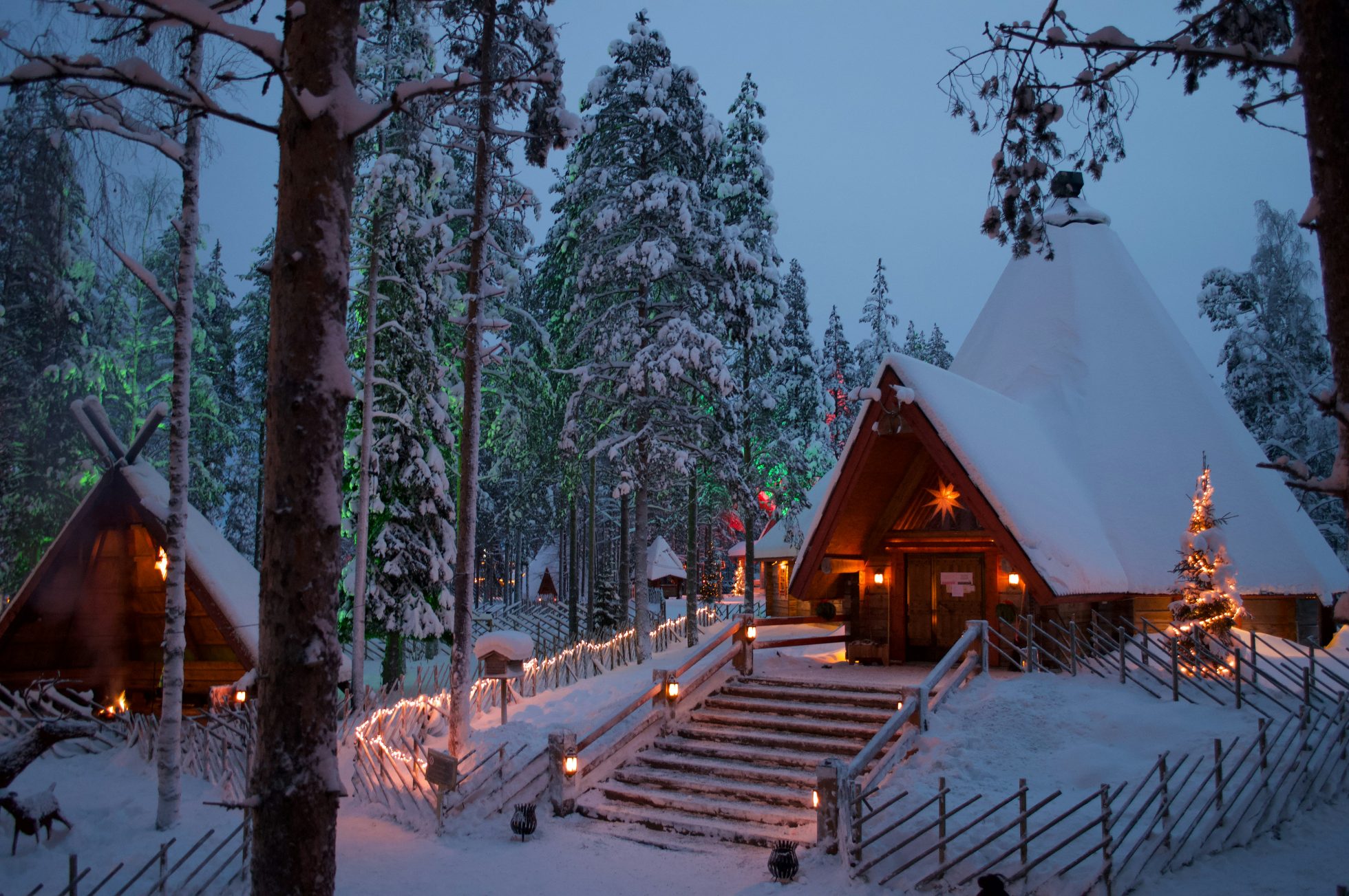 Evening, houses in Santa Claus Village in Rovaniemi, covered with snow and illuminated with lights.