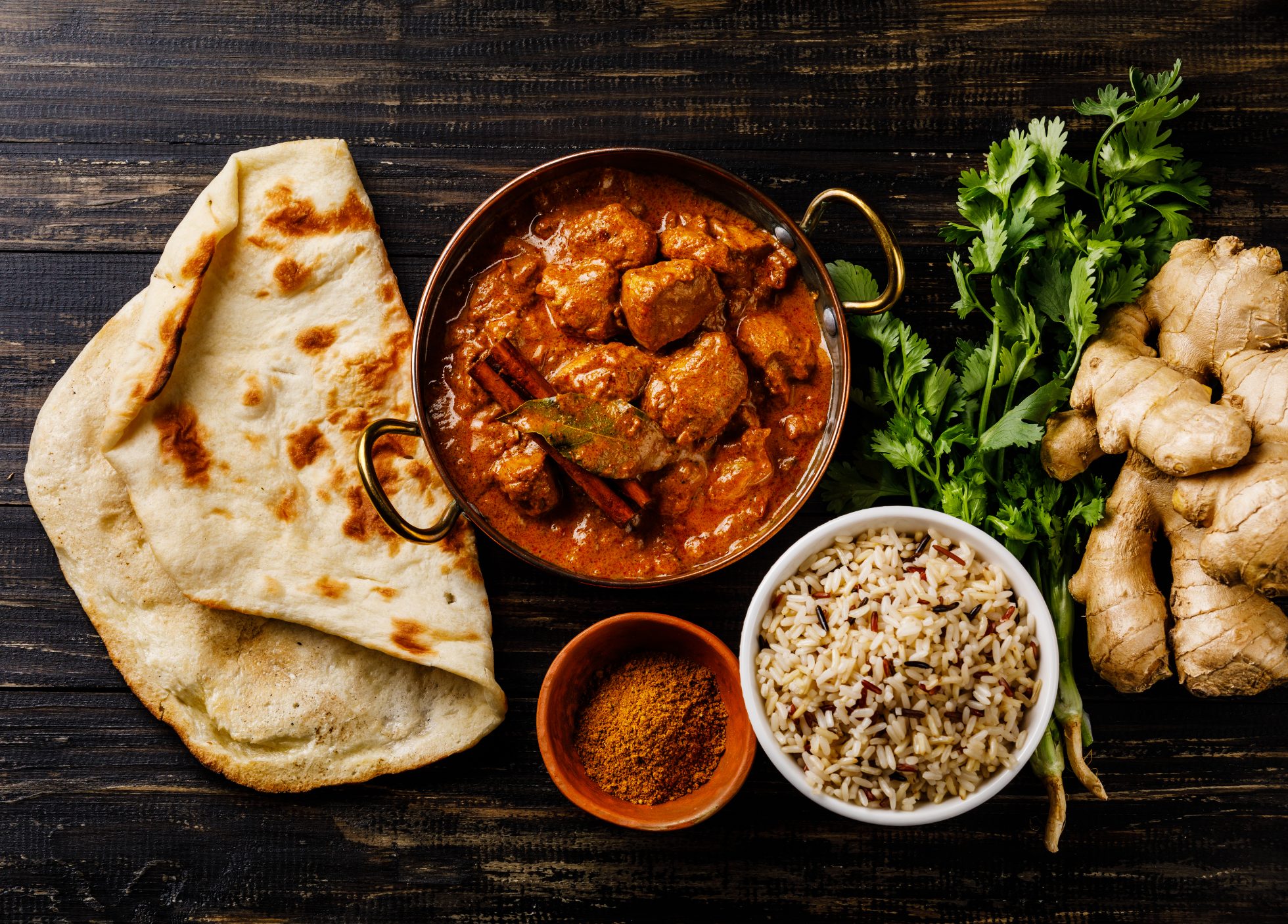 Kurczak curry indyjski na białej misce z ryżem i naanem.
