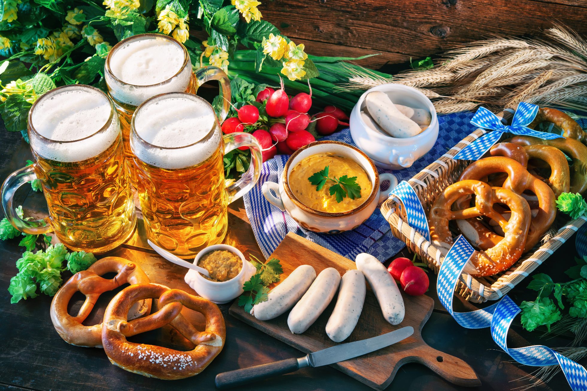 Na obrazku widoczne są niemieckie potrawy na drewnianym stole: kiełbasa, pieczywo, musztarda i kapusta.