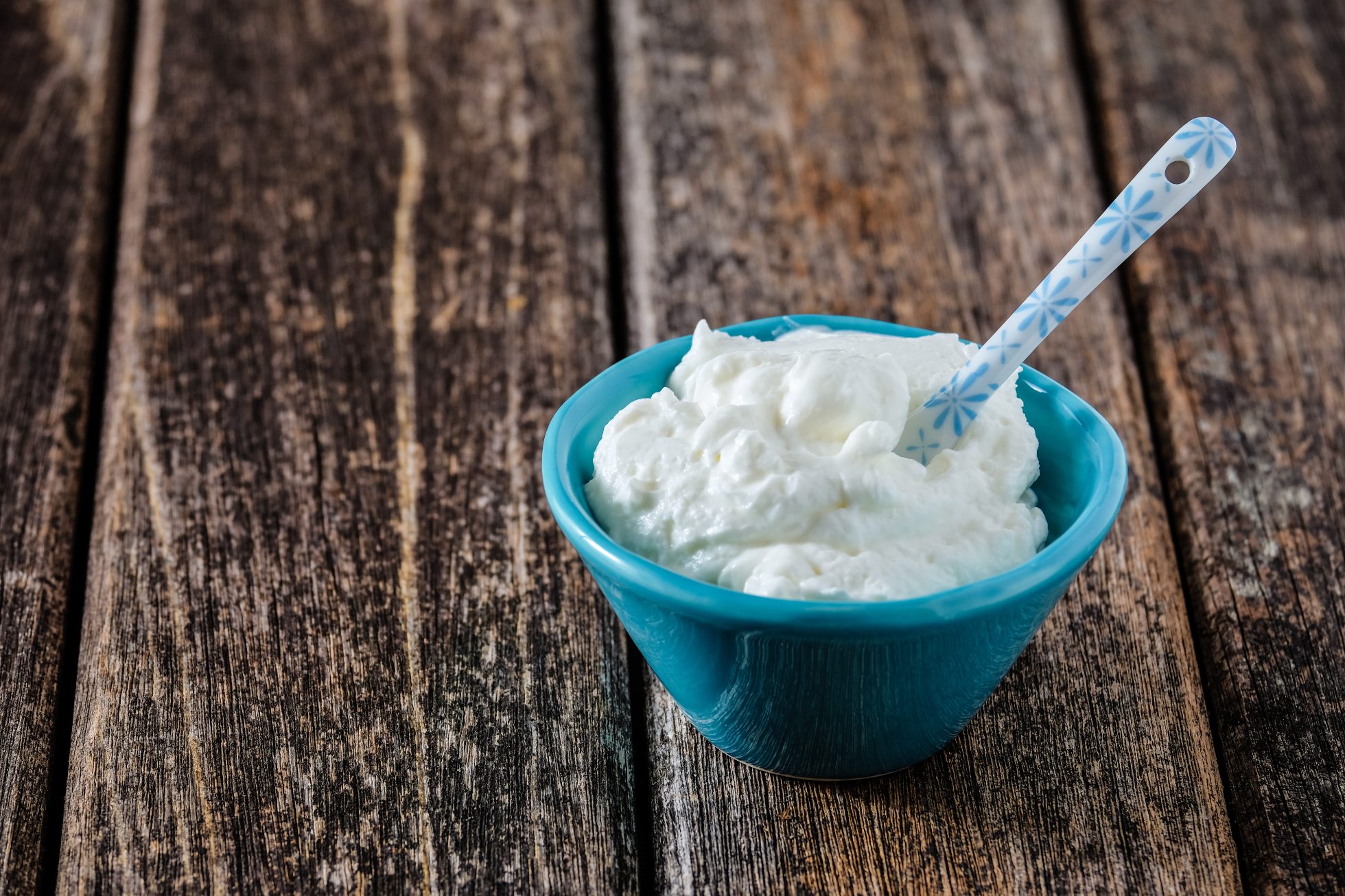 Skyr jogurt twarogowy w niebieskiej misce na drewnianym stole.