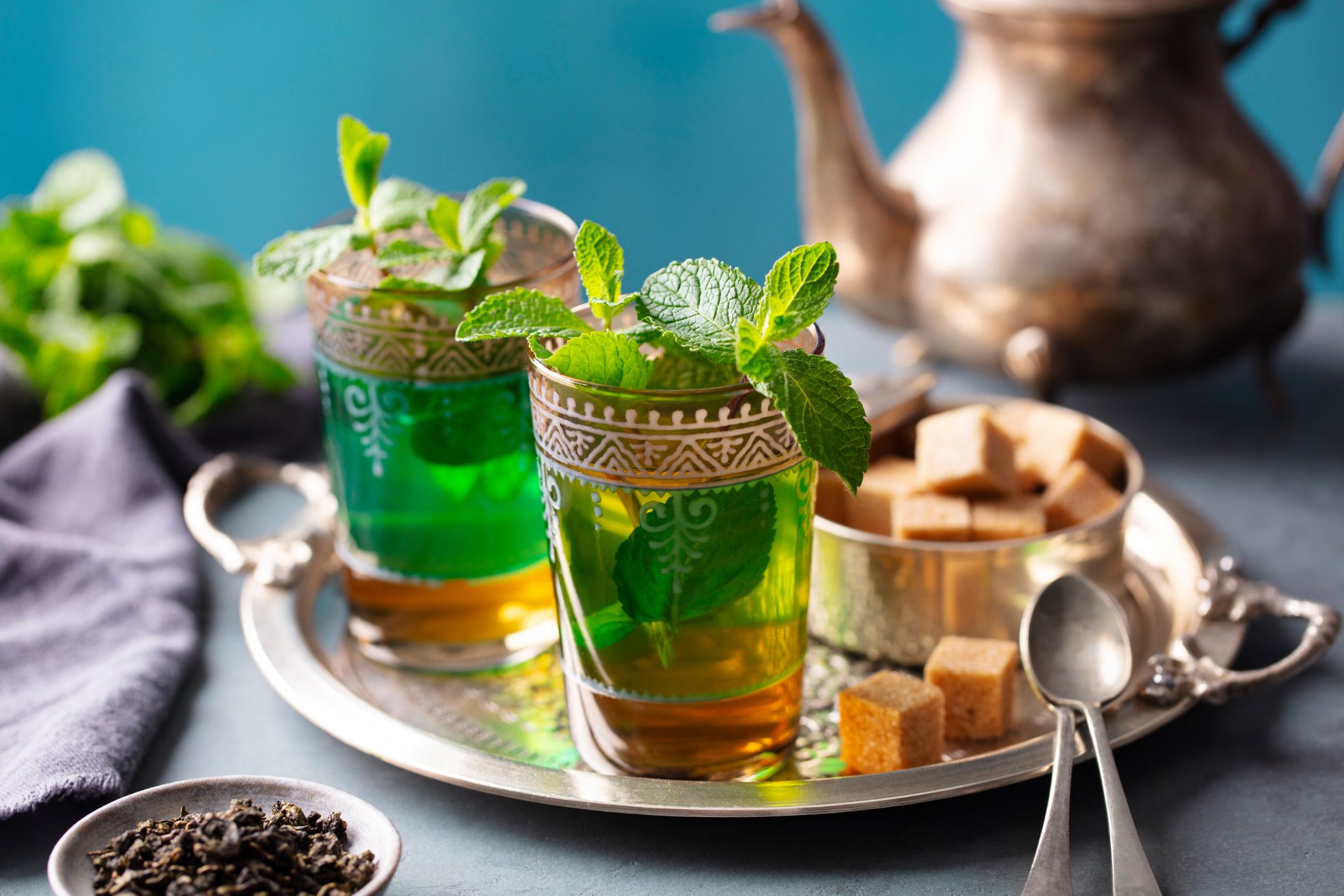 Moroccan mint tea in traditional glasses with sugar on silver tray. Close up.