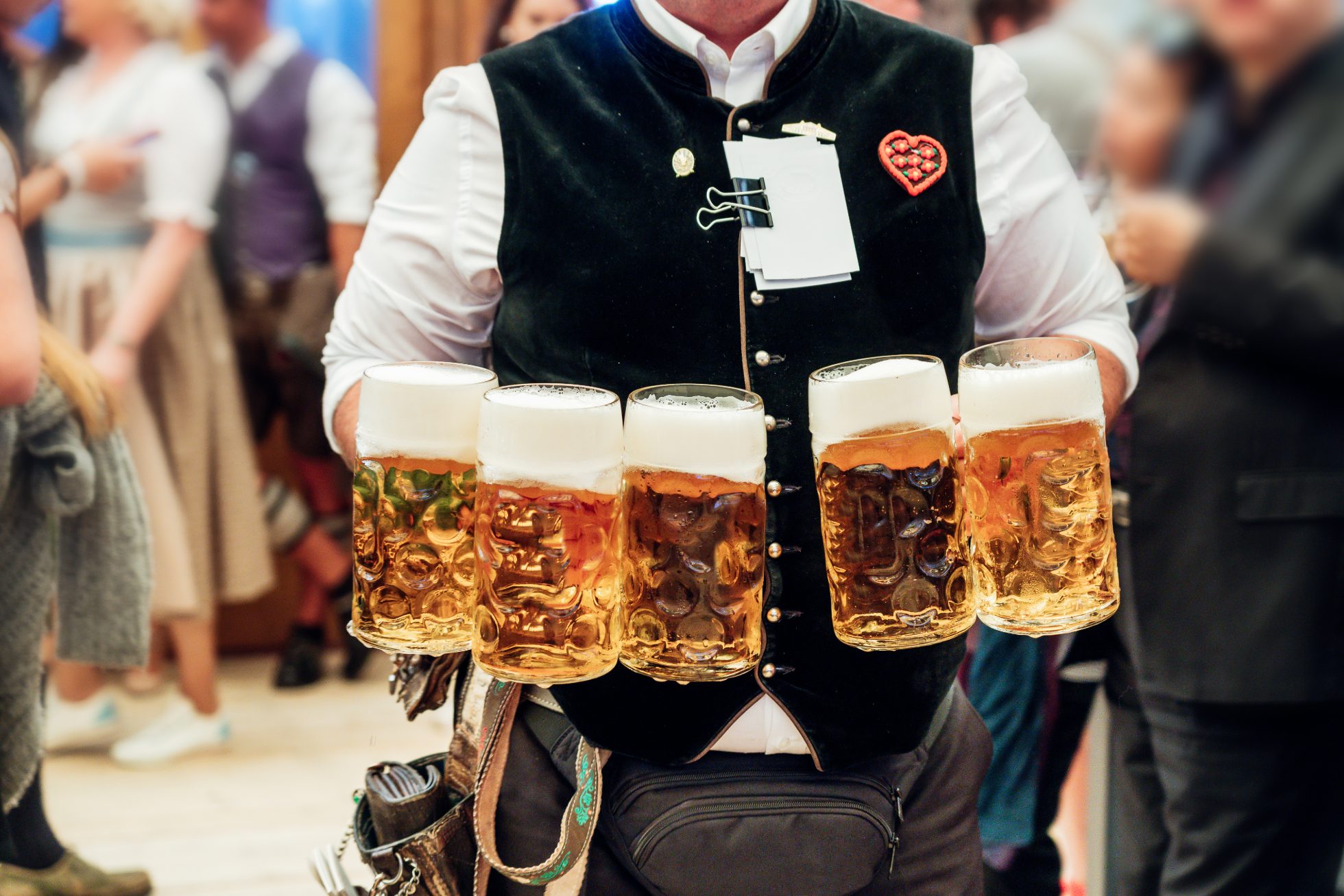 Kufle piwa i kiełbaski na tle tłumu ludzi na Oktoberfest w Niemczech.