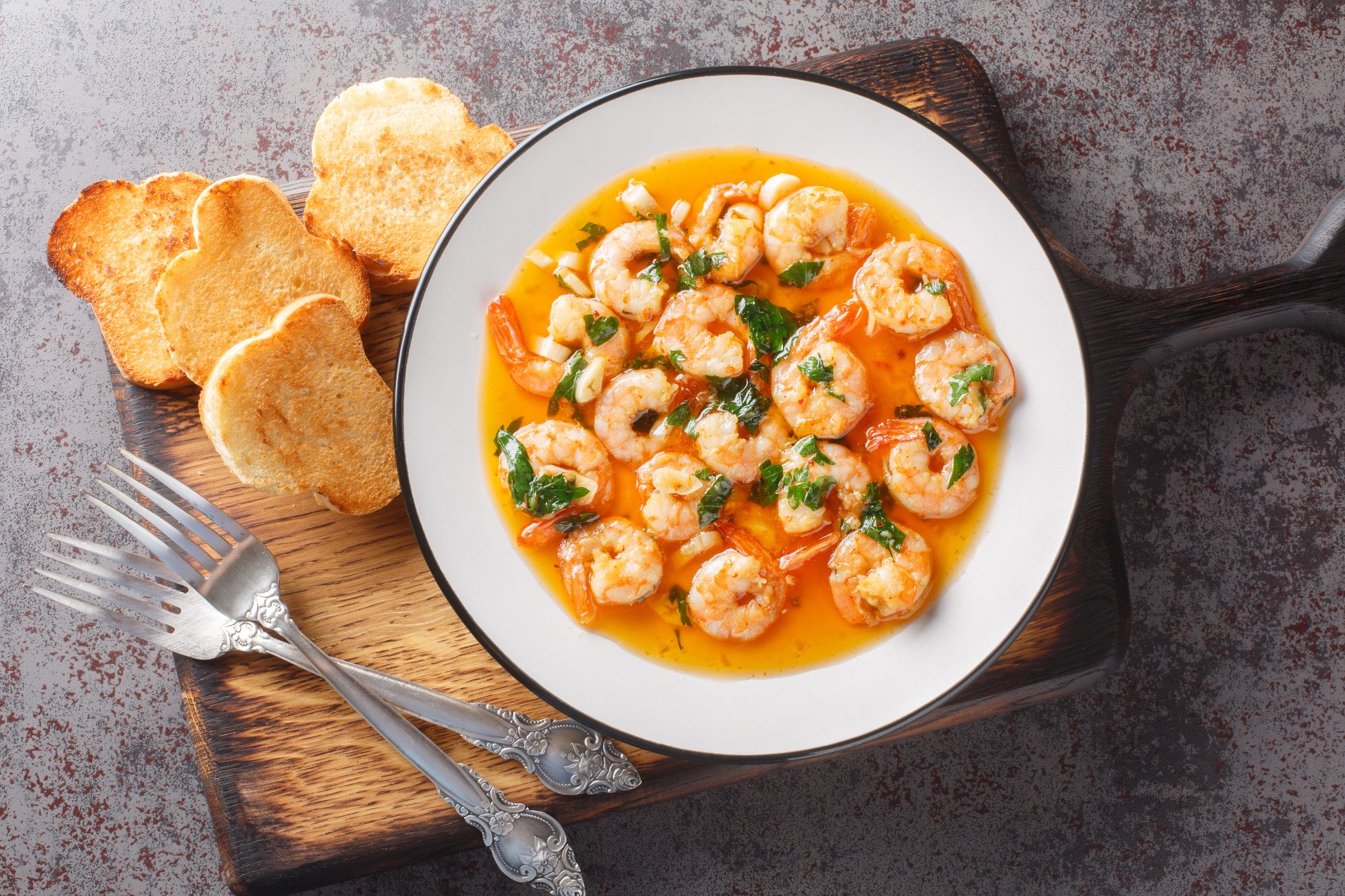 Pyszne krewetki z czosnkiem (Gambas al ajillo) – zbliżenie na drewnianej desce. Widok z góry w poziomie