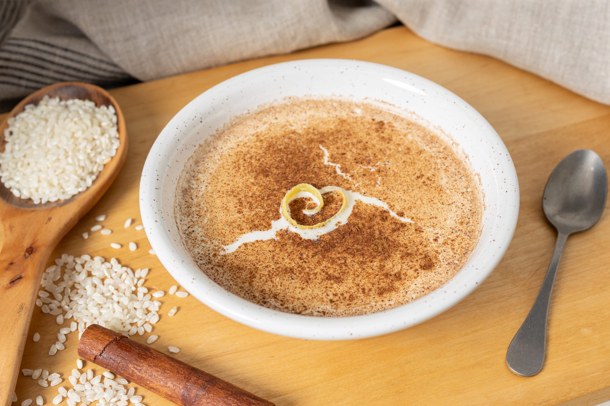 Pudding ryżowy posypany cynamonem i skórką cytrynową w białej misce 