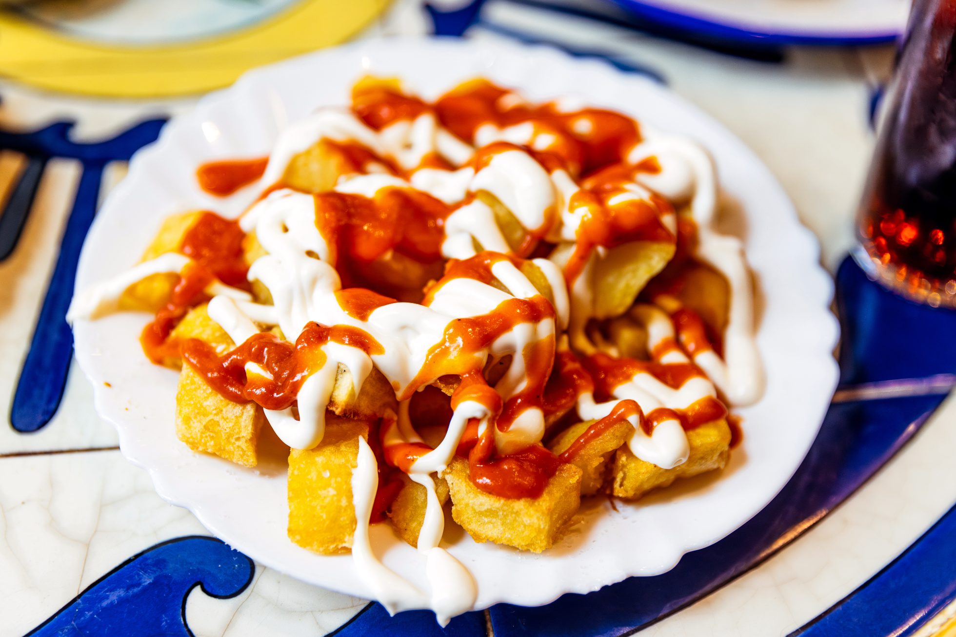 Pieczone ziemniaki podawane z białym sosem aioli i ostrym paprykowym