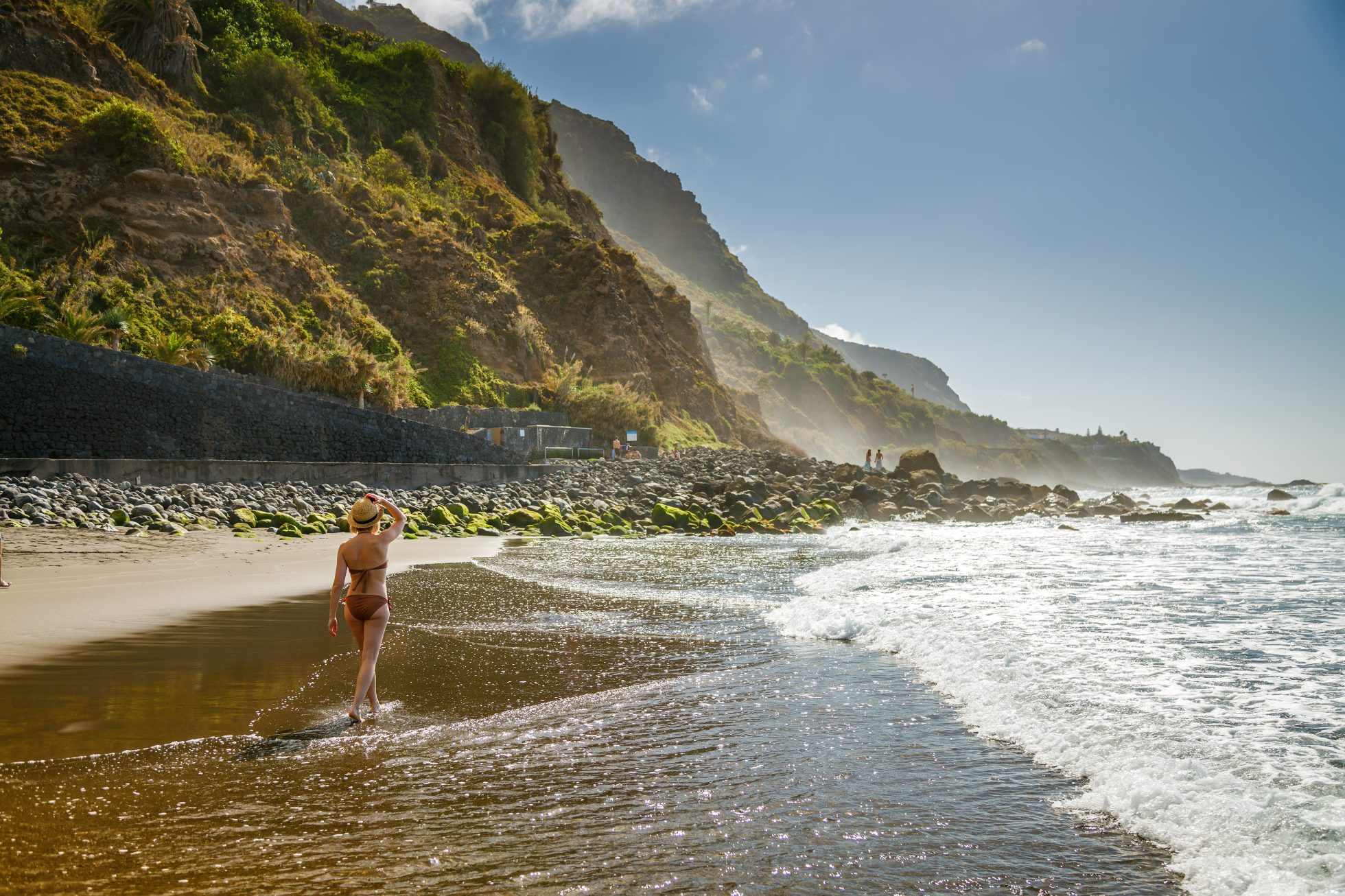 Kobieta w słomkowym kapeluszu spaceruje wzdłuż plaży Playa del Socorro na Teneryfie.