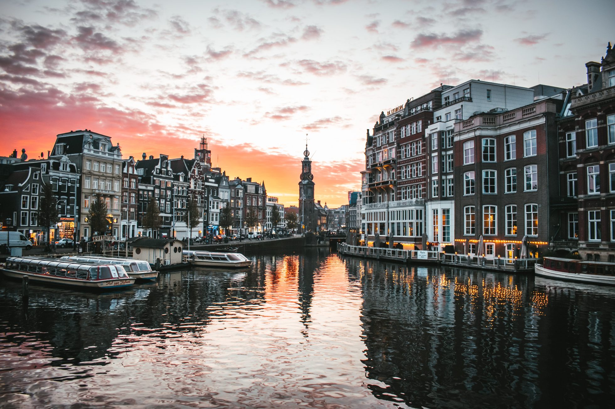 View of Amsterdam's canal and townhouses at sunset; Where to go on vacation in March?