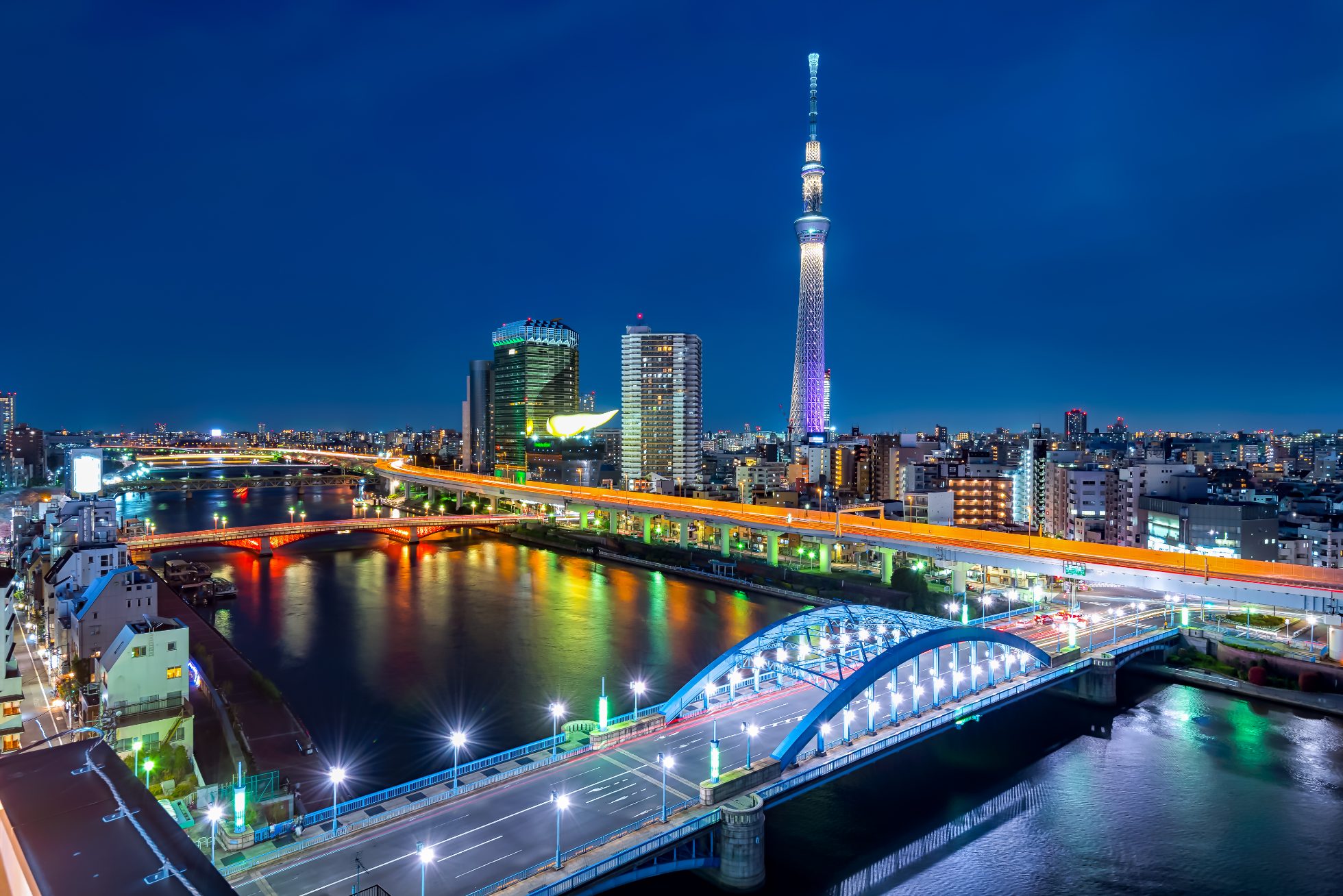 The Tokyo cityscape at night, featuring a view of the Tokyo Skytree and the Asahi building.