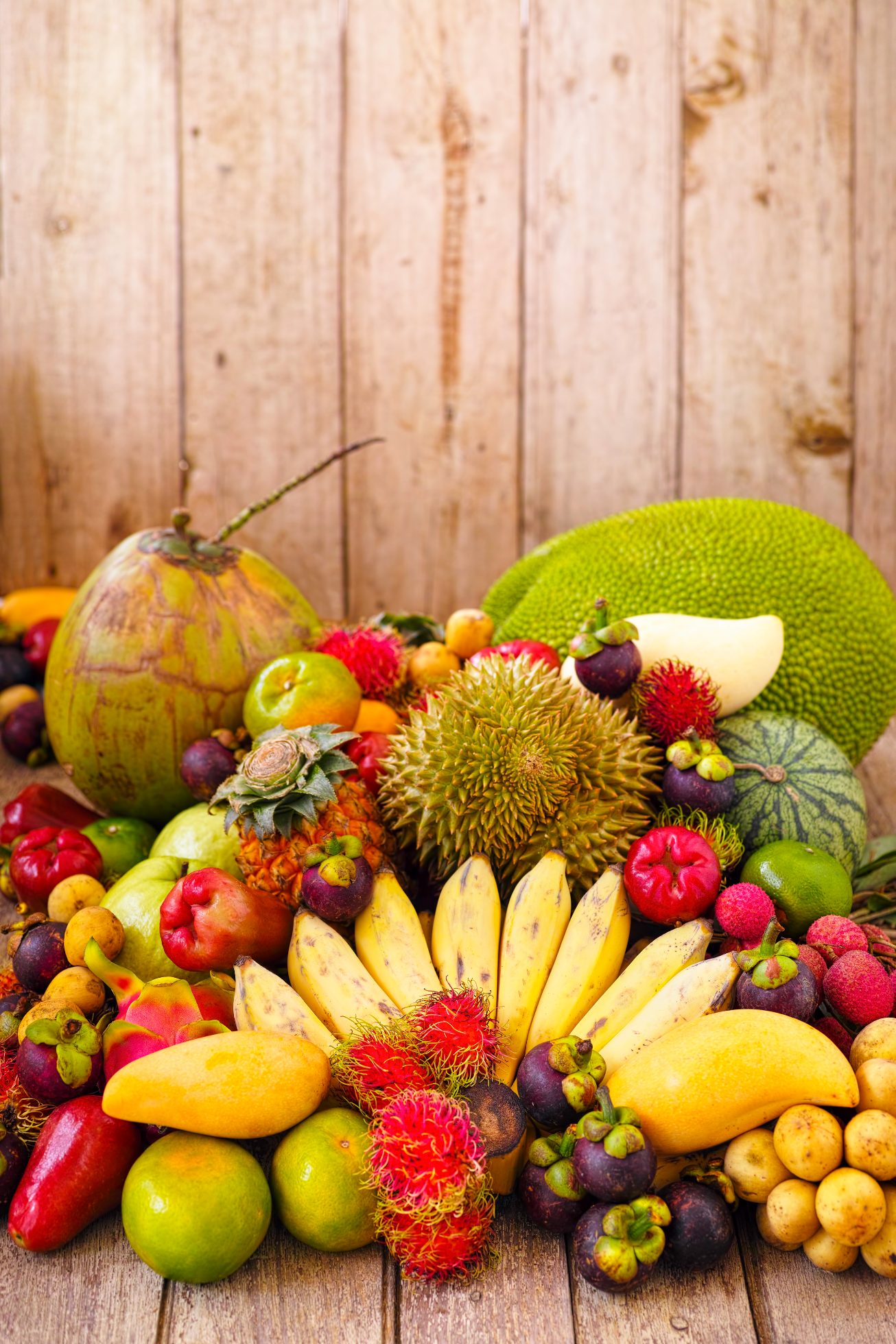 Szeroki wybór znanych, popularnych i świeżych tropikalnych owoców tajskich na starym drewnianym stole. Wśród nich znajdują się: durian, chlebowiec, kokos, mangostan, liczi, jabłko różane, longan, mango, ananas, guawa, rambutan, tajska pomarańcza, mandarynka, tajskie banany, smoczy owoc i arbuz.