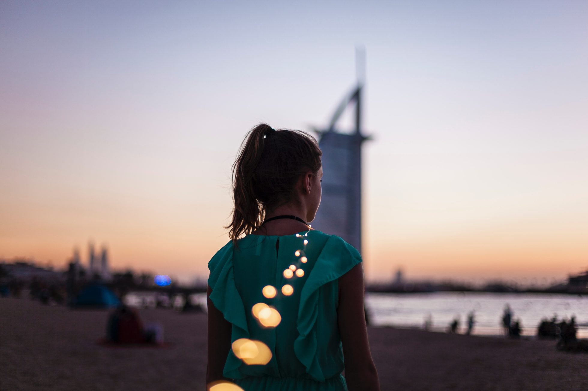 Girl on Dubai beach standing with her back to camera at sunset