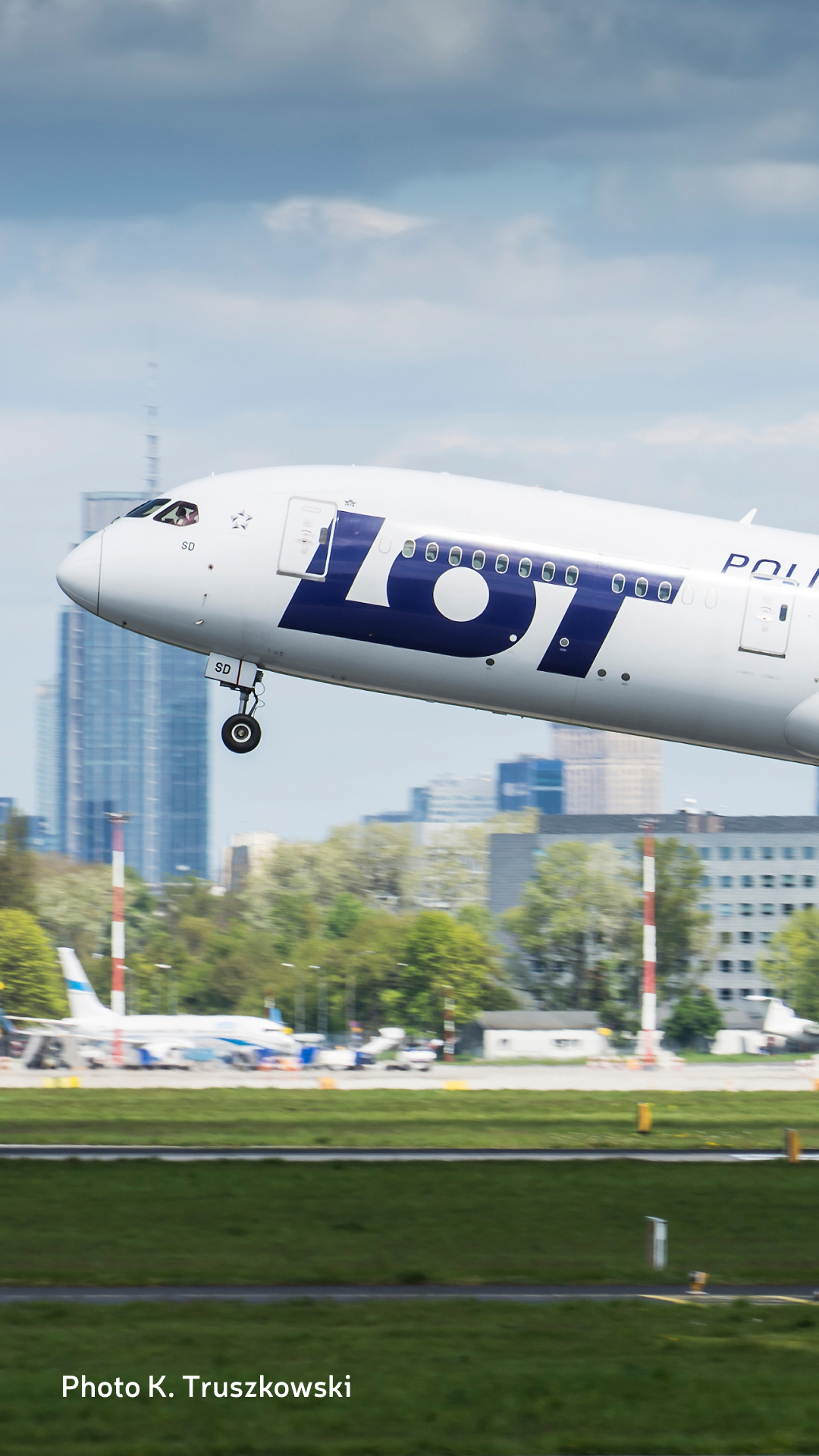 LOT Polish Airlines' Boeing 787 Dreamliner taking off on a sunny day from Chopin Airport with Warsaw in the background