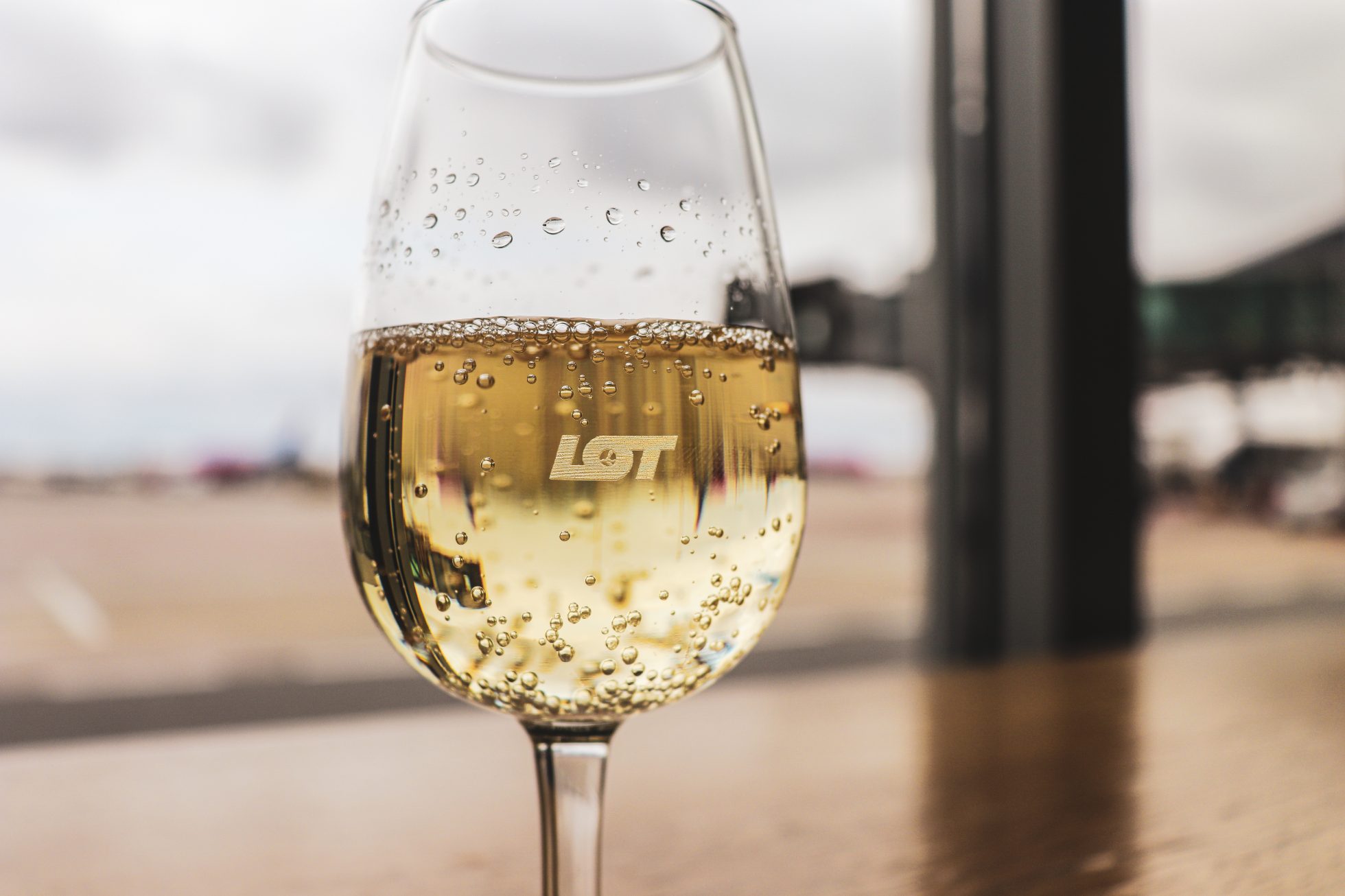 sparkling wine glass with engraved LOT lettering and airport tarmac in the background