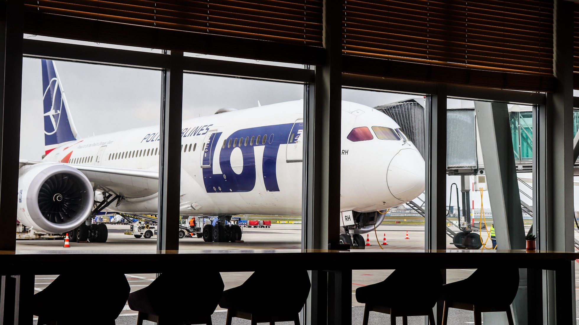 panoramiczne szyby z widokiem na 787 Dreamliner stojący na płycie lotniska - LOT Business Lounge Mazurek