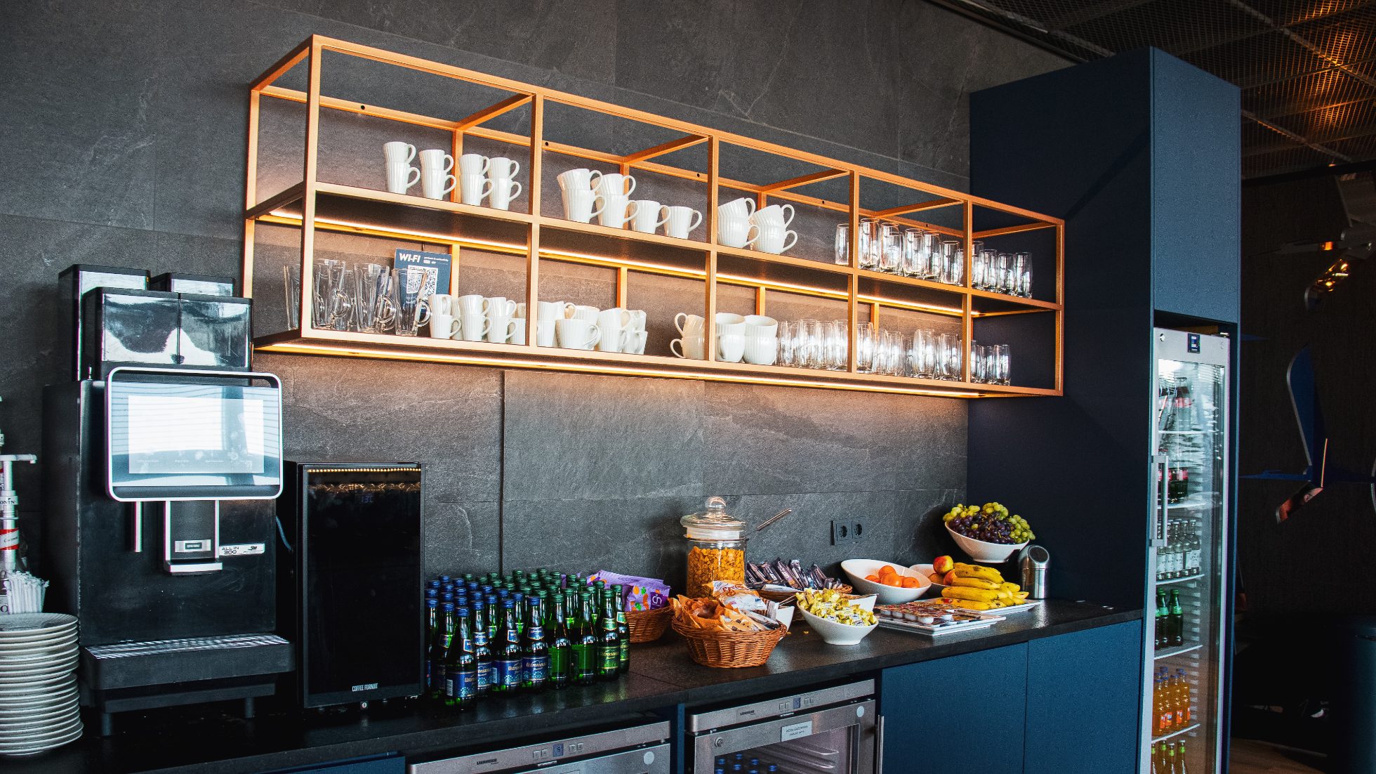 Drinks and snacks area in the LOT Business Lounge Mazurek - bars, apples, nuts. Glass bottles of water and coffee machine