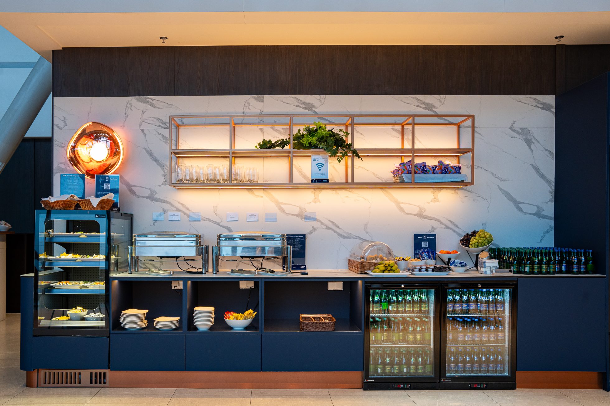 Moderne Einrichtung im LOT Business Lounge Polonez - Blick auf den Küchenbereich mit Snacks und Getränken.