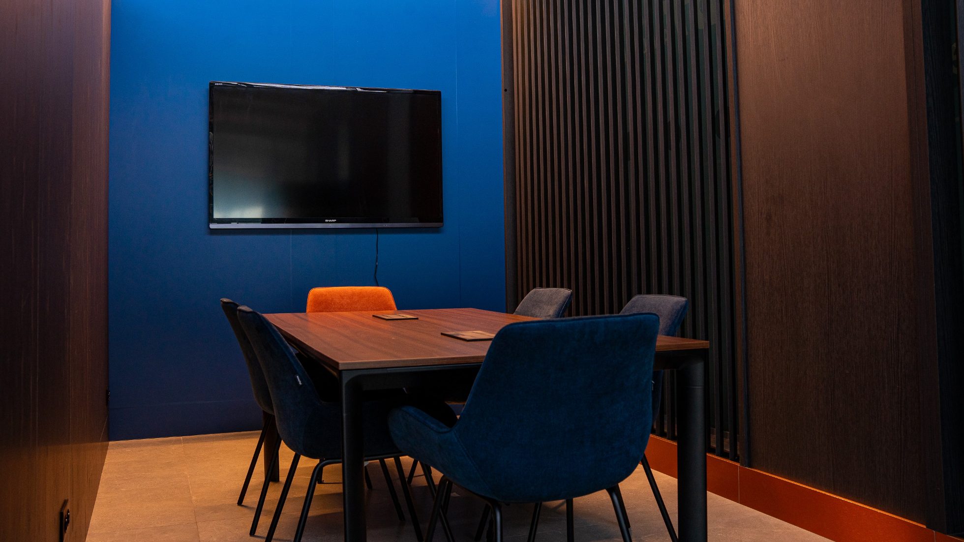 Sala konferencyjna w LOT Business Lounge Polonez - stół i sześć krzeseł, telewizor, granatowe ściany.