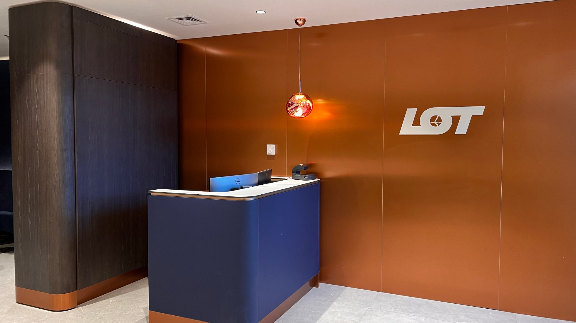 A Polonez Gold Lounge belső tere – kanapék és ülőszékek, a LOT logójával ellátott fal és réz lámpák.