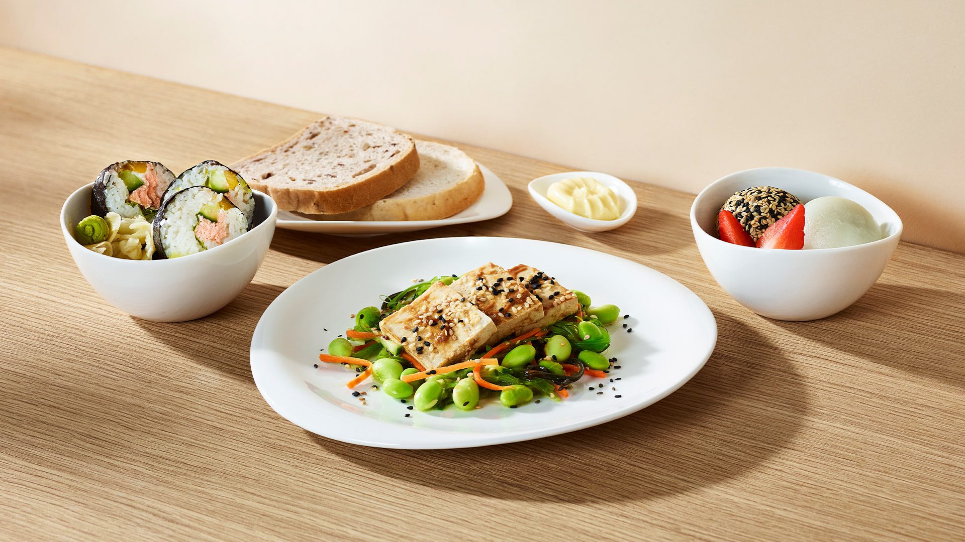 Sałatka z wakame, tofu, edamame i prażonym sezamem w sosie Hoisin. Zestaw sushi z łososiem podany z pastą wasabi i marynowanym imbirem. Na słodko – dwa mochi z dodatkiem świeżych truskawek. Podany z bezglutenowym pieczywem i masłem. 