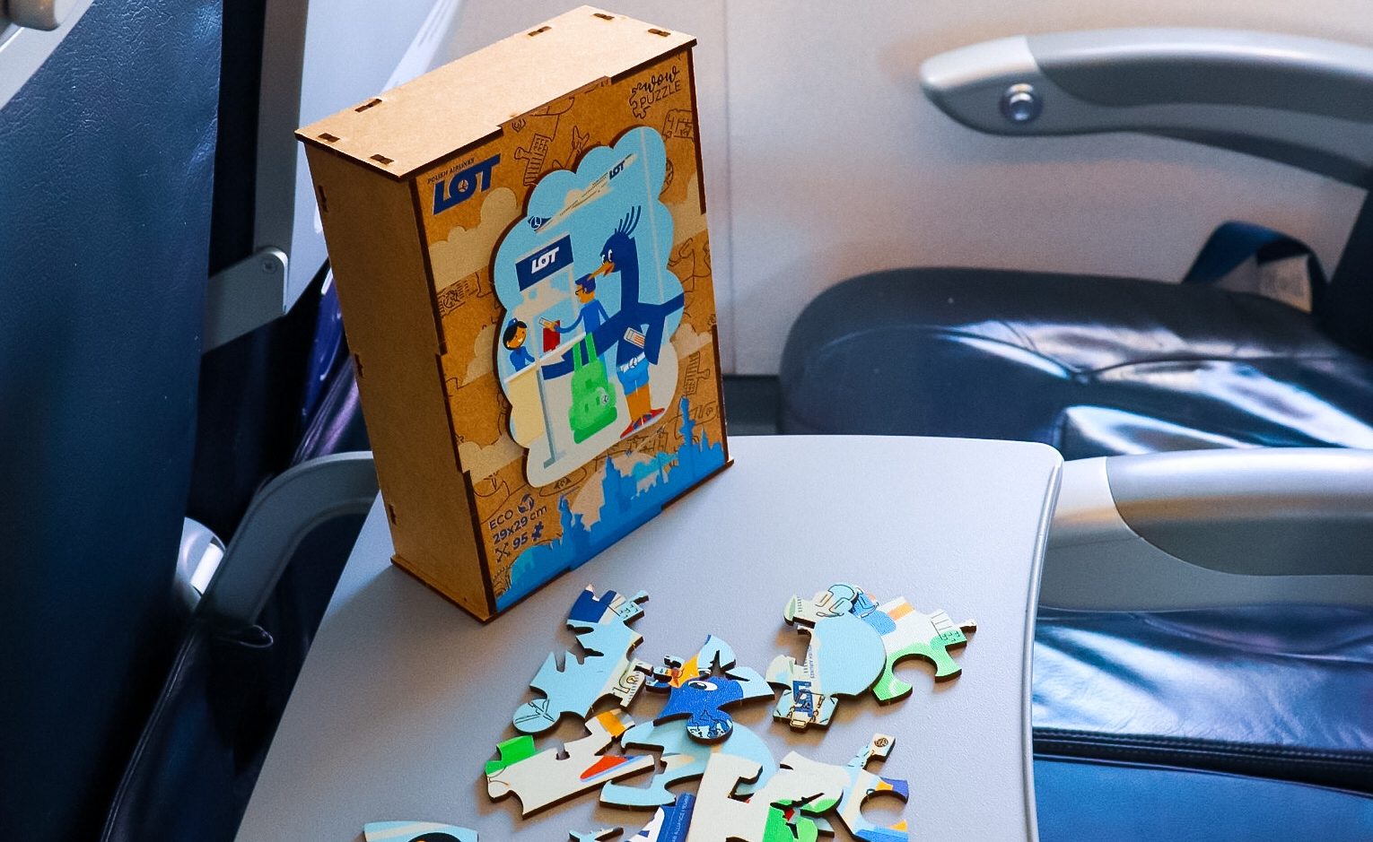Drewniane puzzle ekologiczne z żurawiem LOTkiem na stoliku na pokładzie samolotu