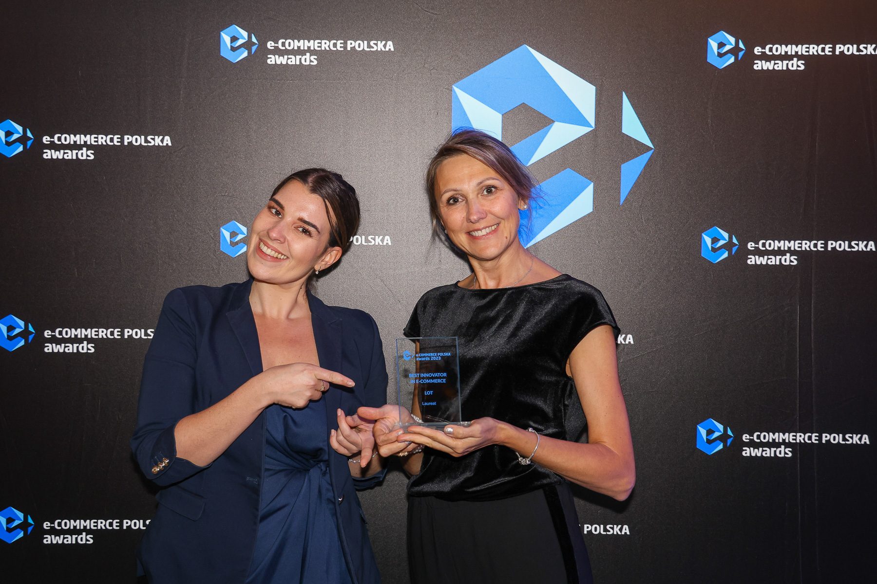 Osoba trzymająca statuetkę e-commerce award na tle logo LOT.