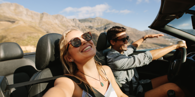 A group of friends driving a car during the day in a warm country.