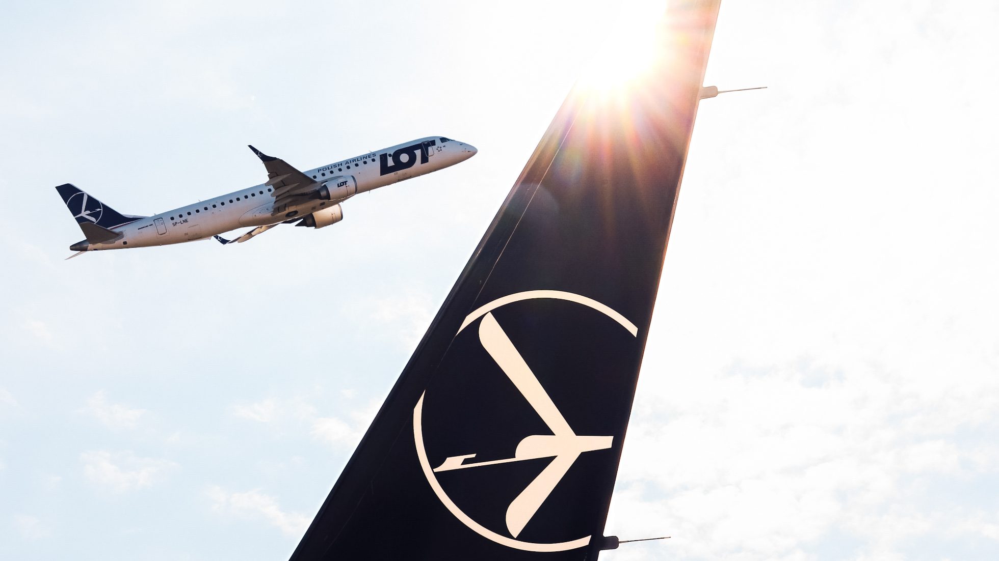 Skrzydło Boeing 737 MAX 8 z logo Crane i Embraer 190 odlatywujący w tle w słoneczny dzień.