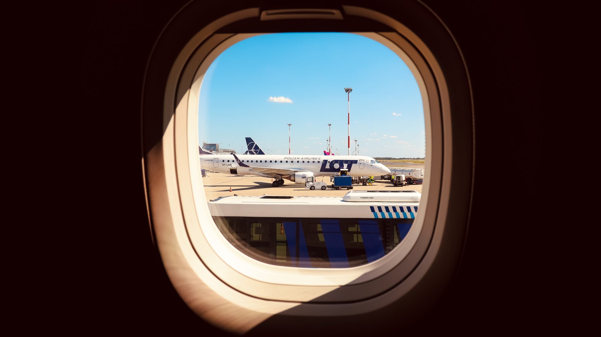 Okno samolotu Embraer E2 z widokiem na skrzydło i niebo.