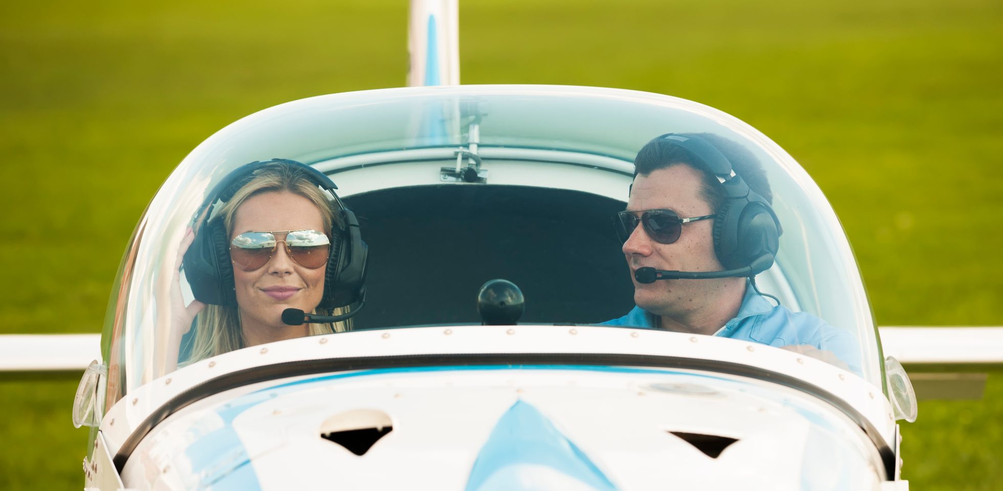 Kobieta i mężczyzna pilot w samolocie, patrzą na kamerę, przygotowując się do lotu.