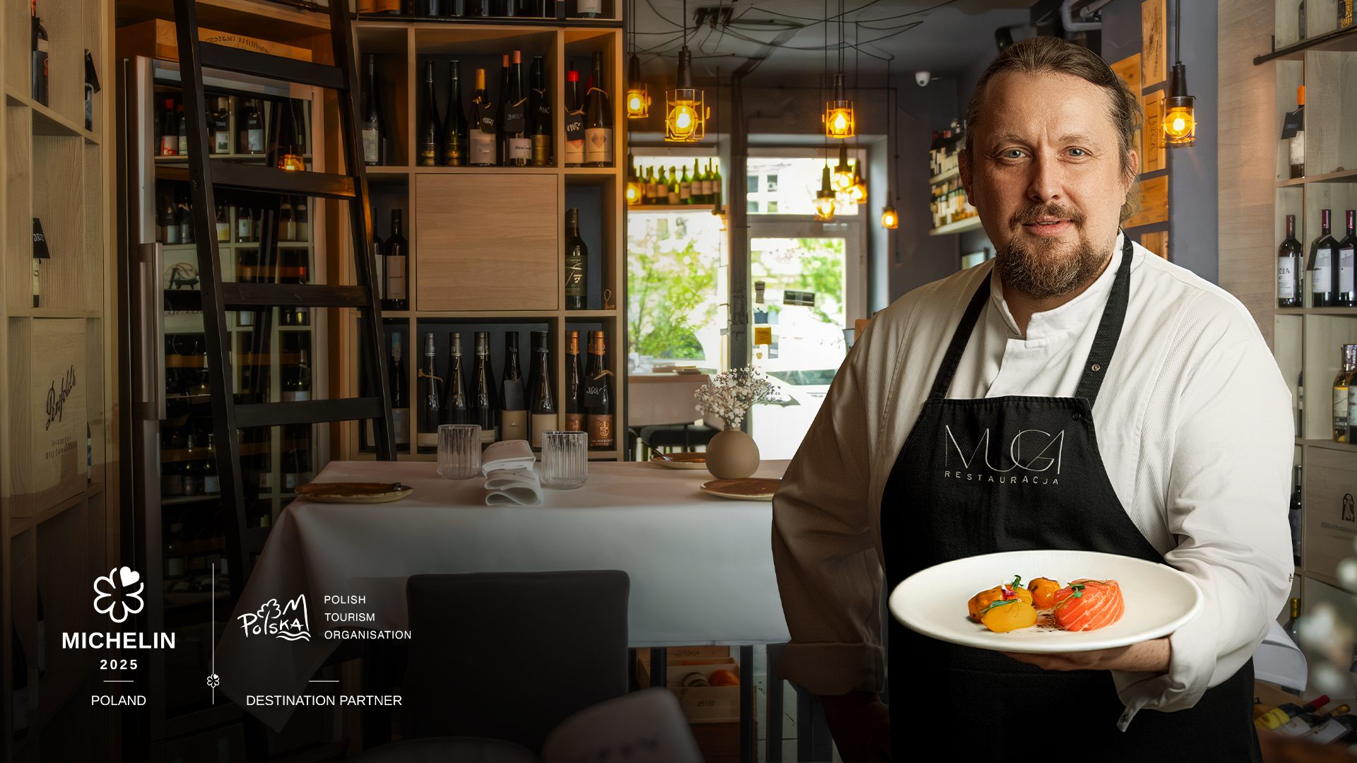 Artur Stokarczyk, head chef at Muga restaurant, standing with a plate of food in his restaurant