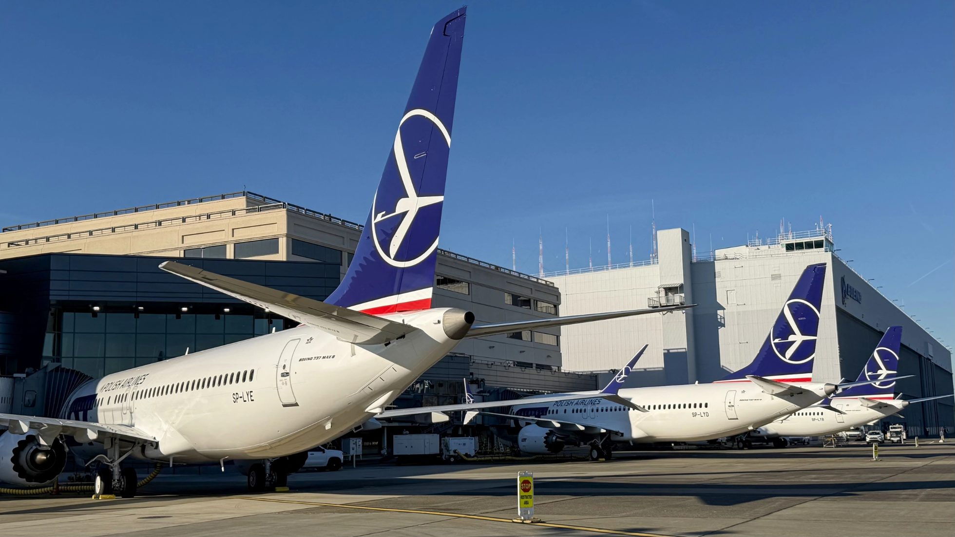 Trzy samoloty Boeing 737 MAX 8 LOT-u zaparkowane obok siebie na lotnisku w Seattle w bezchmurny dzień