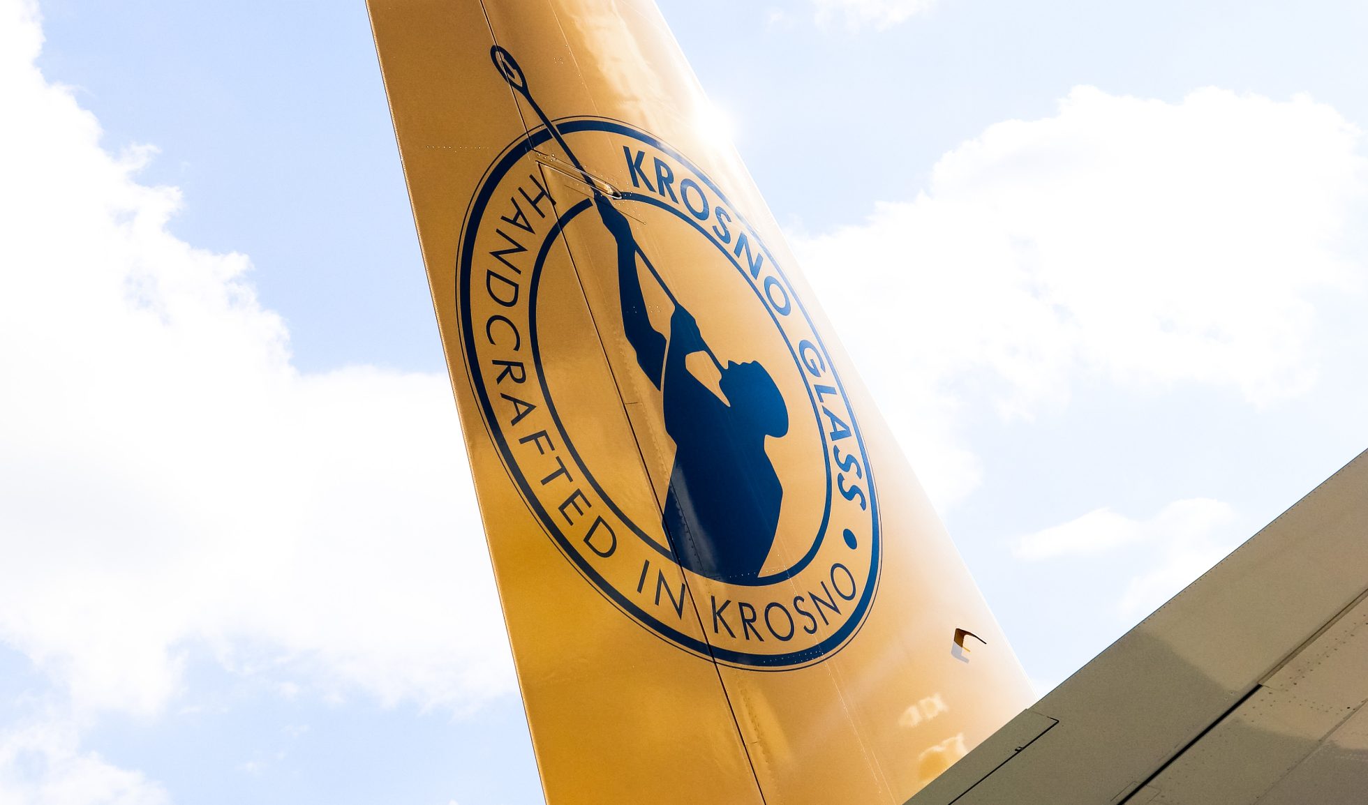 Boeing 737 MAX ballast in gold color, with black graphic of glass blower and KROSNO inscription