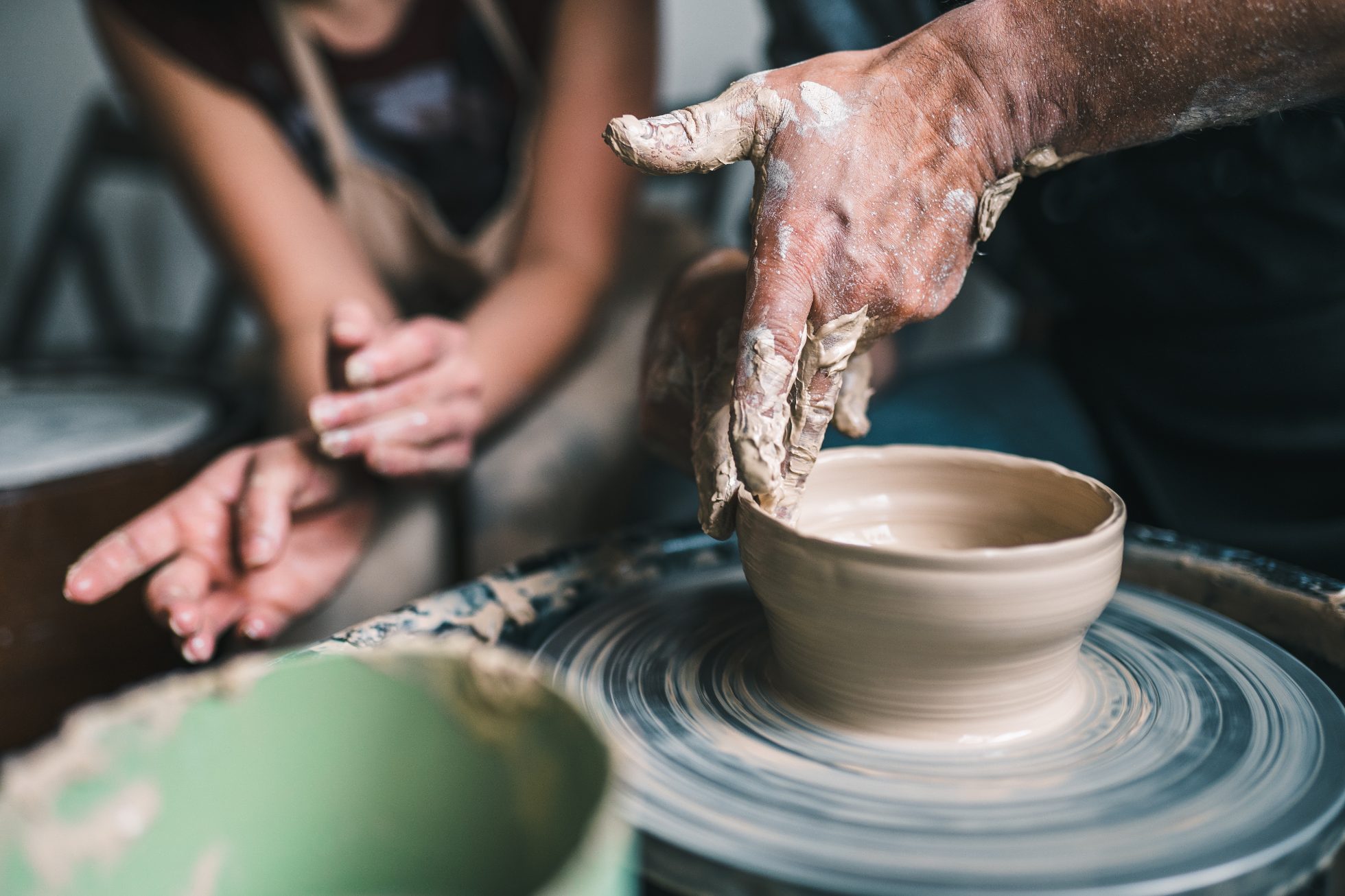 Osoba lepiąca gliniane naczynie na warsztacie ceramicznym.
