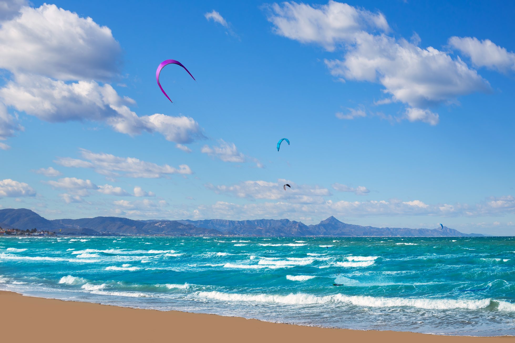 Piasek, morze, niebieskie niebo i parasole plażowe na plaży Gandia na Costa Blanca.