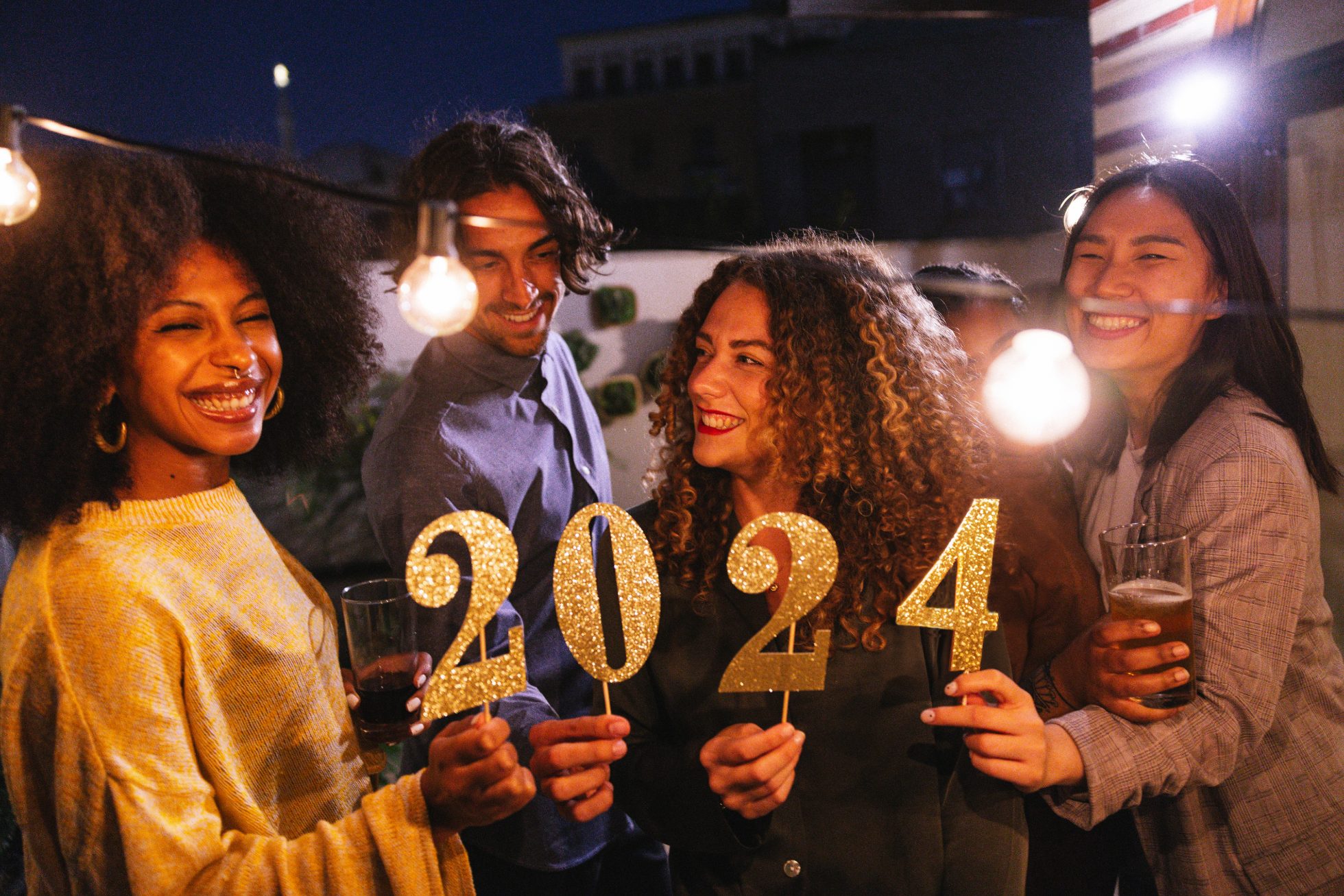Group of friends holding the number 2024, celebration conceptual image for New Yearâs Eve.