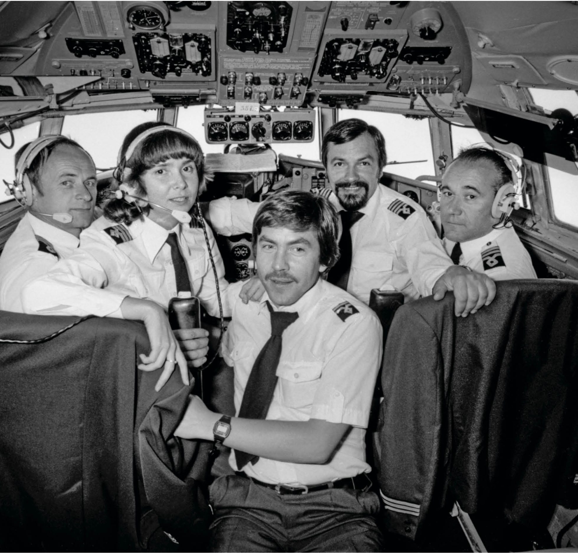 A black and white photo of LOT pilots in the cockpit.