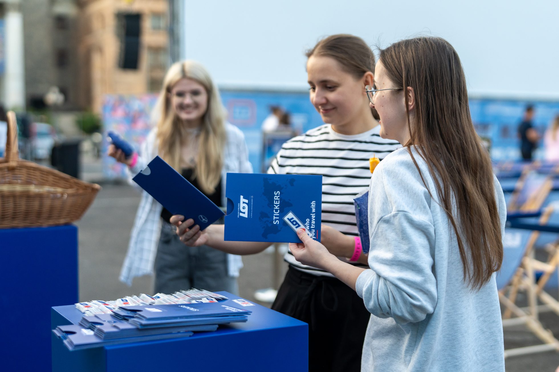 dwie dziewczyny częstujące się zestawem naklejek LOT-u w strefie promocyjnej PLL LOT 