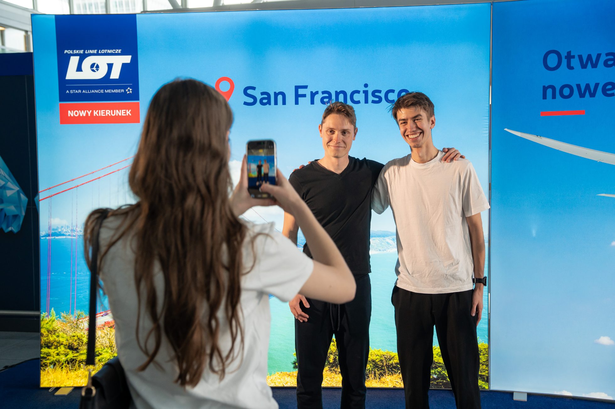 Passengers taking photos in front of a backdrop to mark the launch of the route to San Francisco