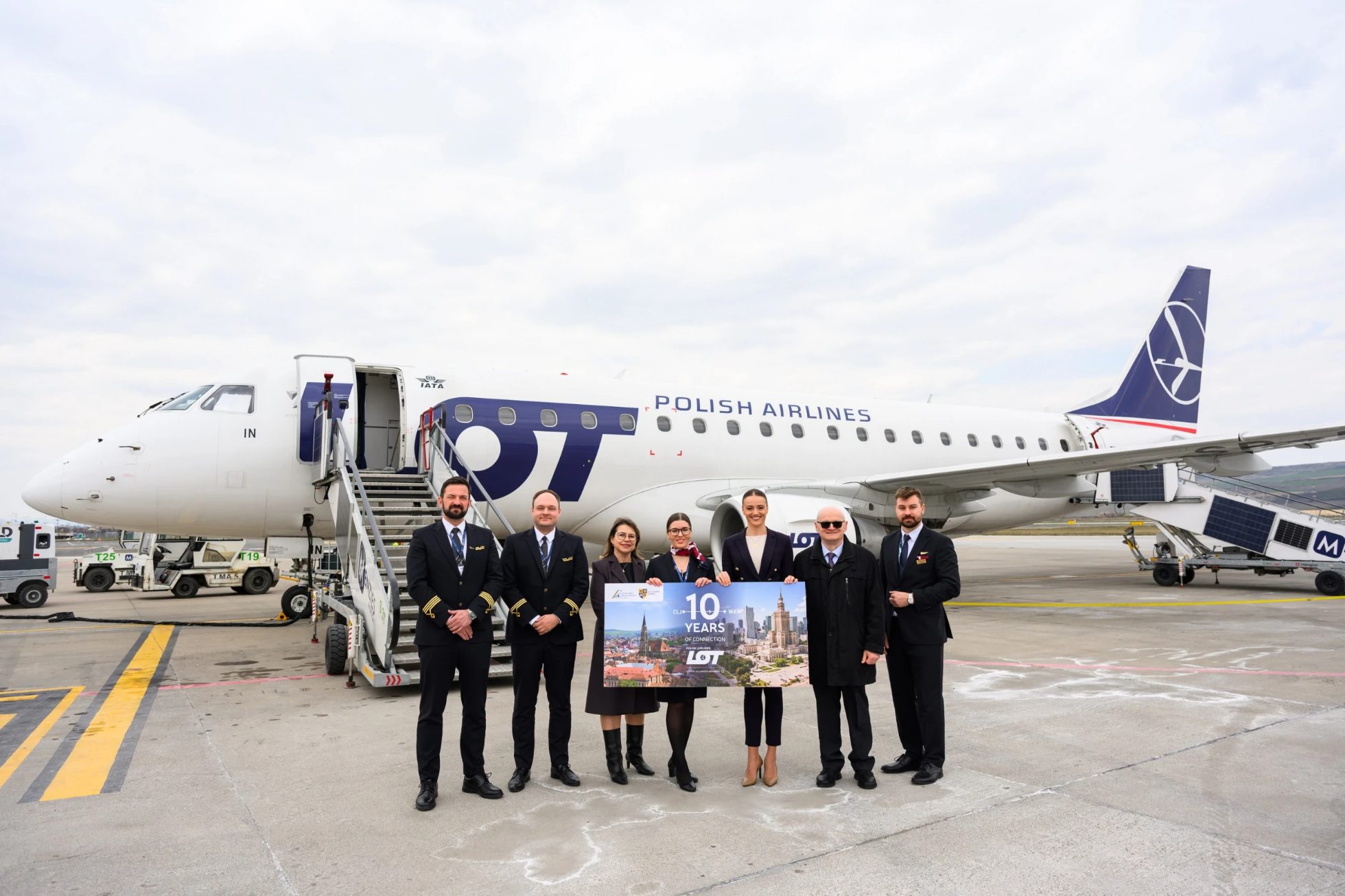 An Embraer 175 aircraft at Cluj-Napoca Airport with airport representatives and a four-member flight crew