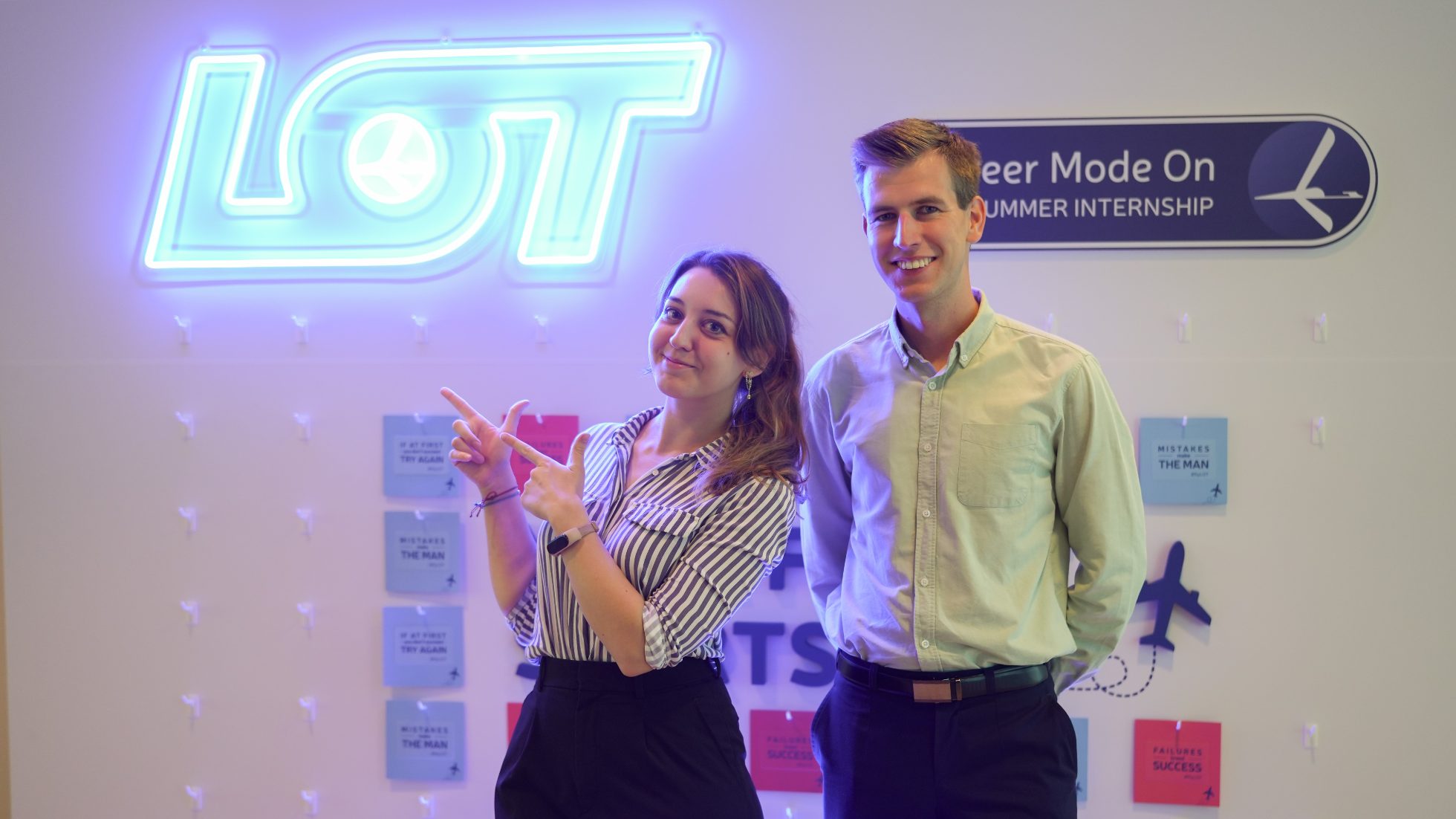 Young woman and man in office, with LOT neon logo in background