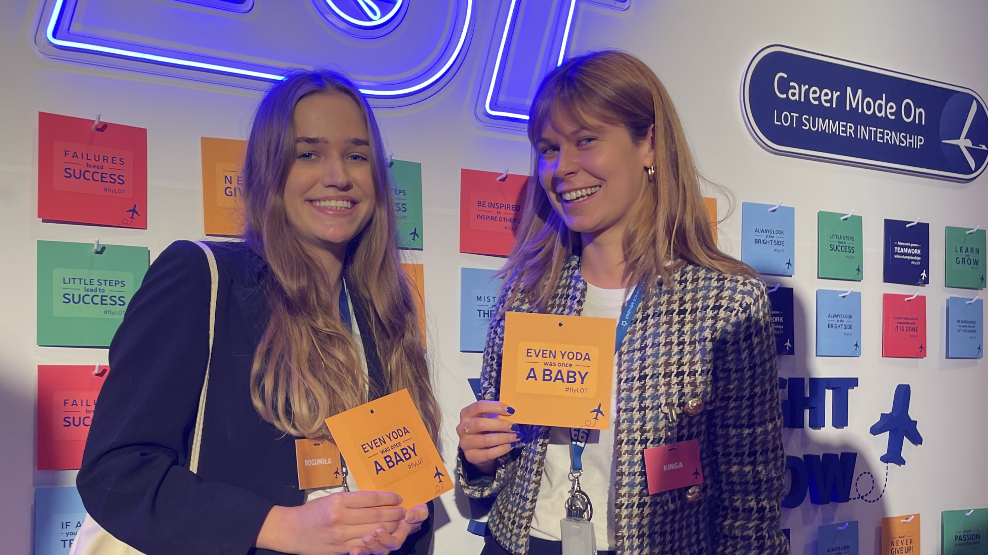 Two women smiling against a wall and LOT neon logo