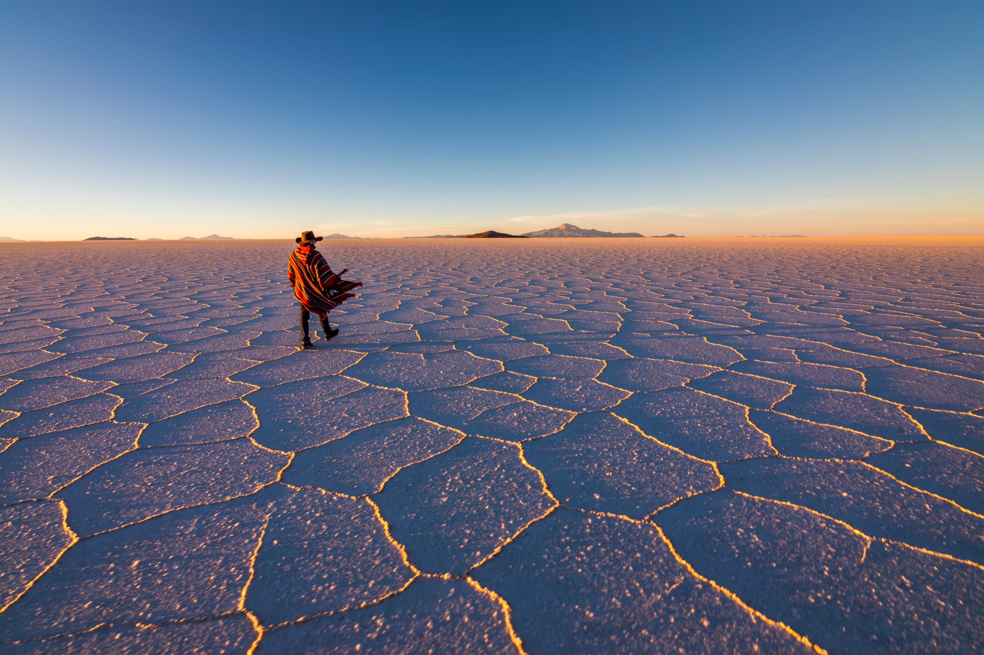 Szeroki krajobraz solniska Salar de Uyuni w Boliwii. Błękitne niebo odbija się w lustrzanym jeziorze soli.