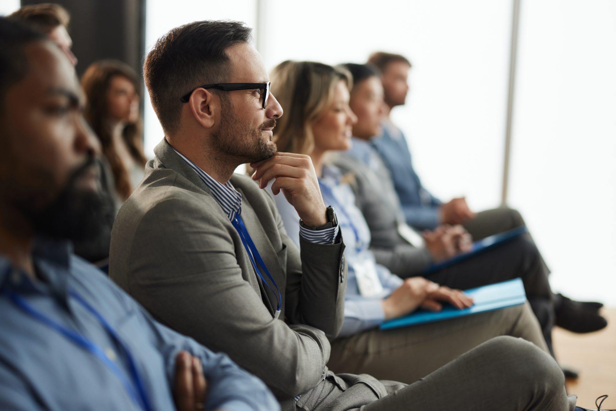Widok z profilu uśmiechniętego biznesmena i grupy jego kolegów uczestniczących w seminarium w sali konferencyjnej.