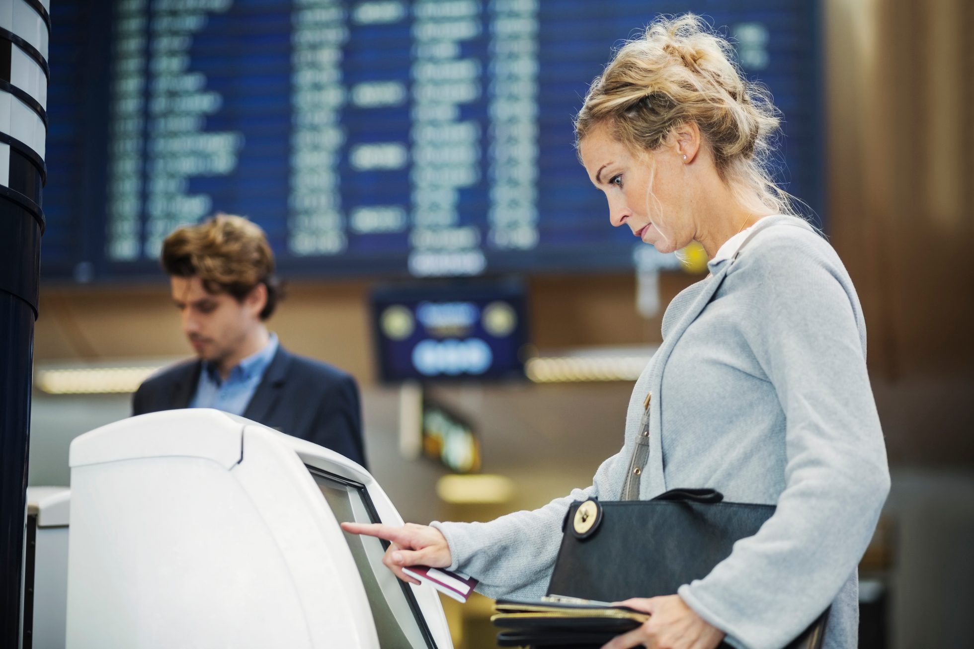 The passenger is checking in at the kiosk at the airport