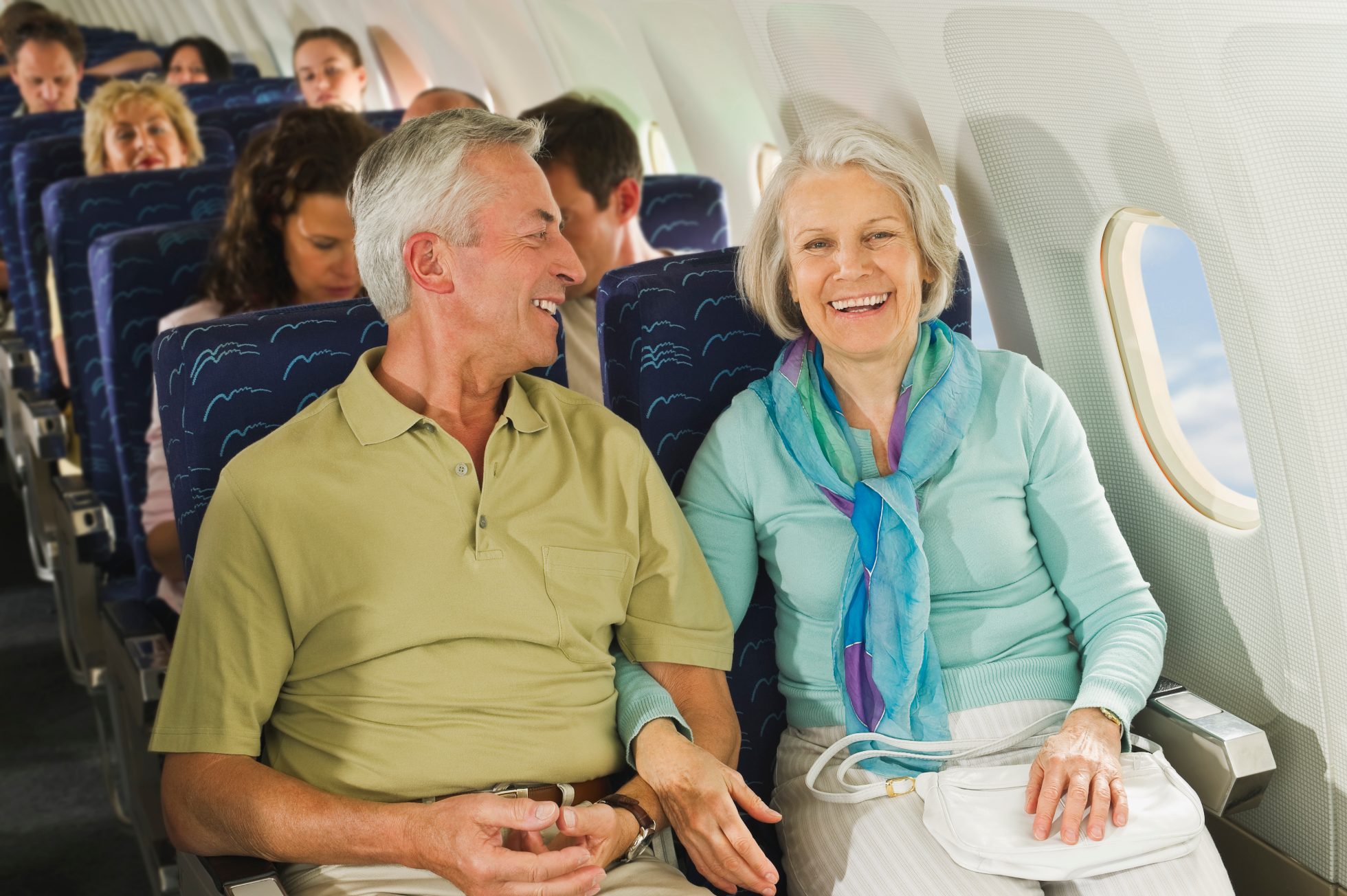 A pair of happy seniors laugh while sitting on a plane in nice weather