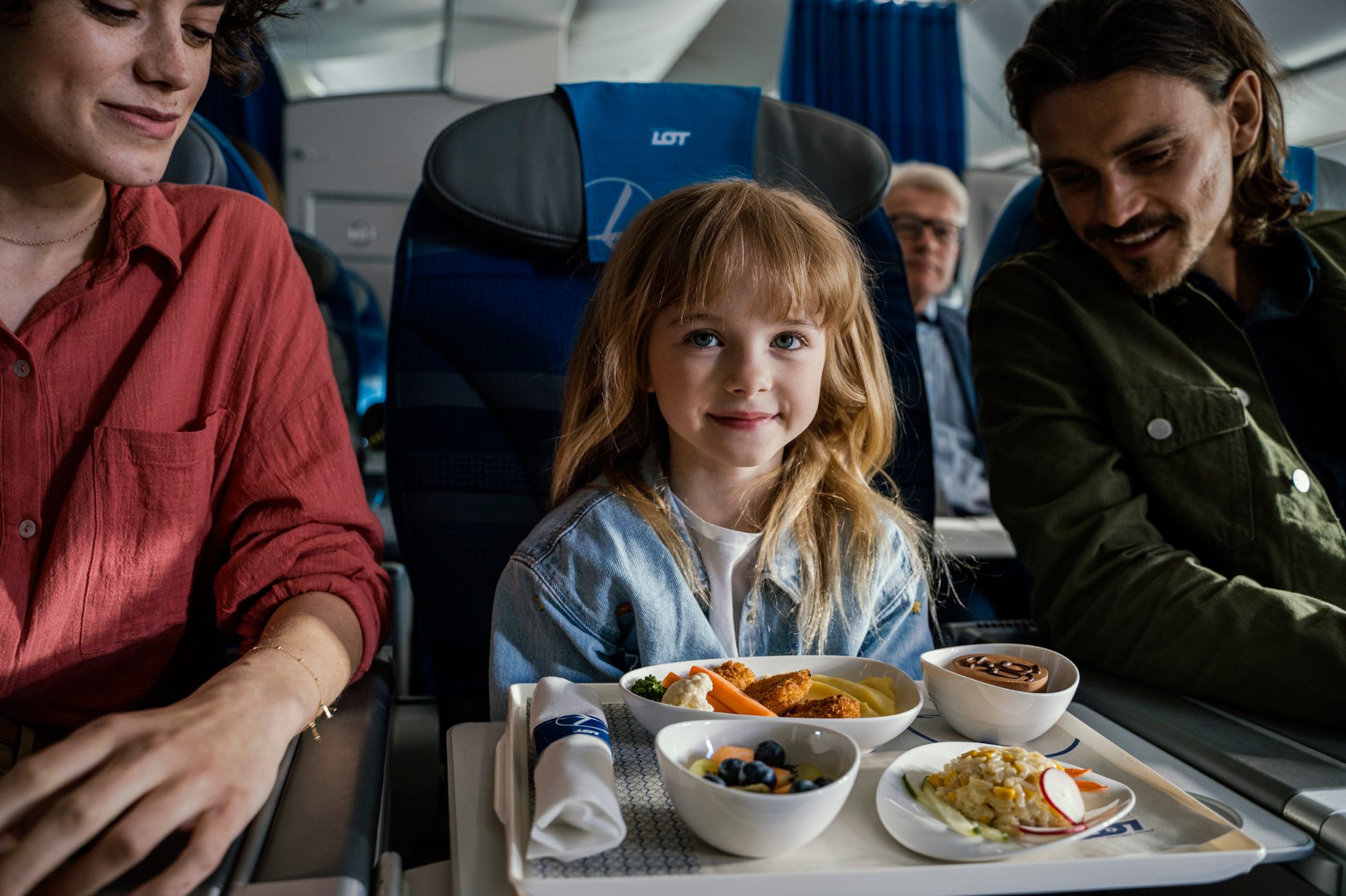 Person sitting in airplane seat with a meal.