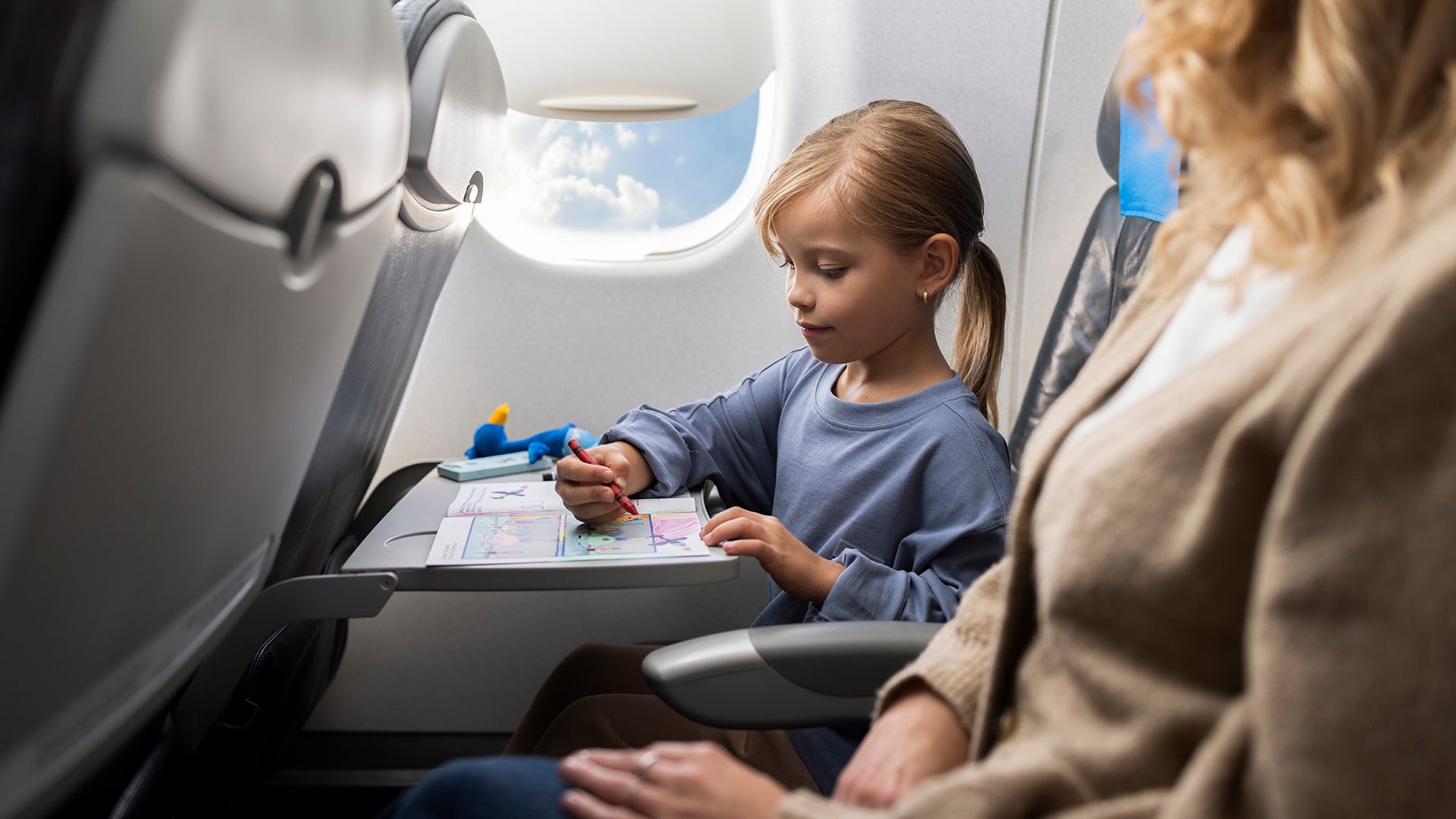 una niña jugando con libros para colorear a bordo de un Embraer
