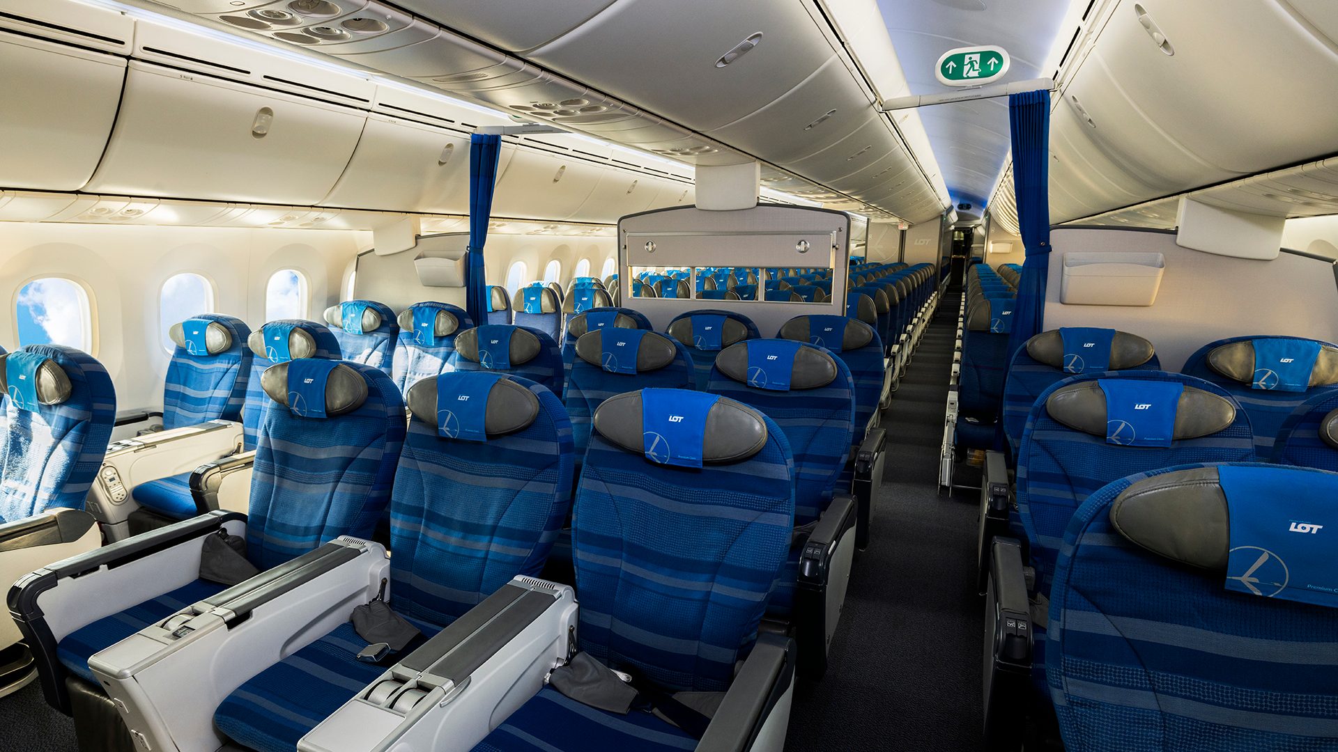 Kabina LOT Premium Economy, rząd foteli w układzie 2-3-2, schowki bagażowe i duże okna.