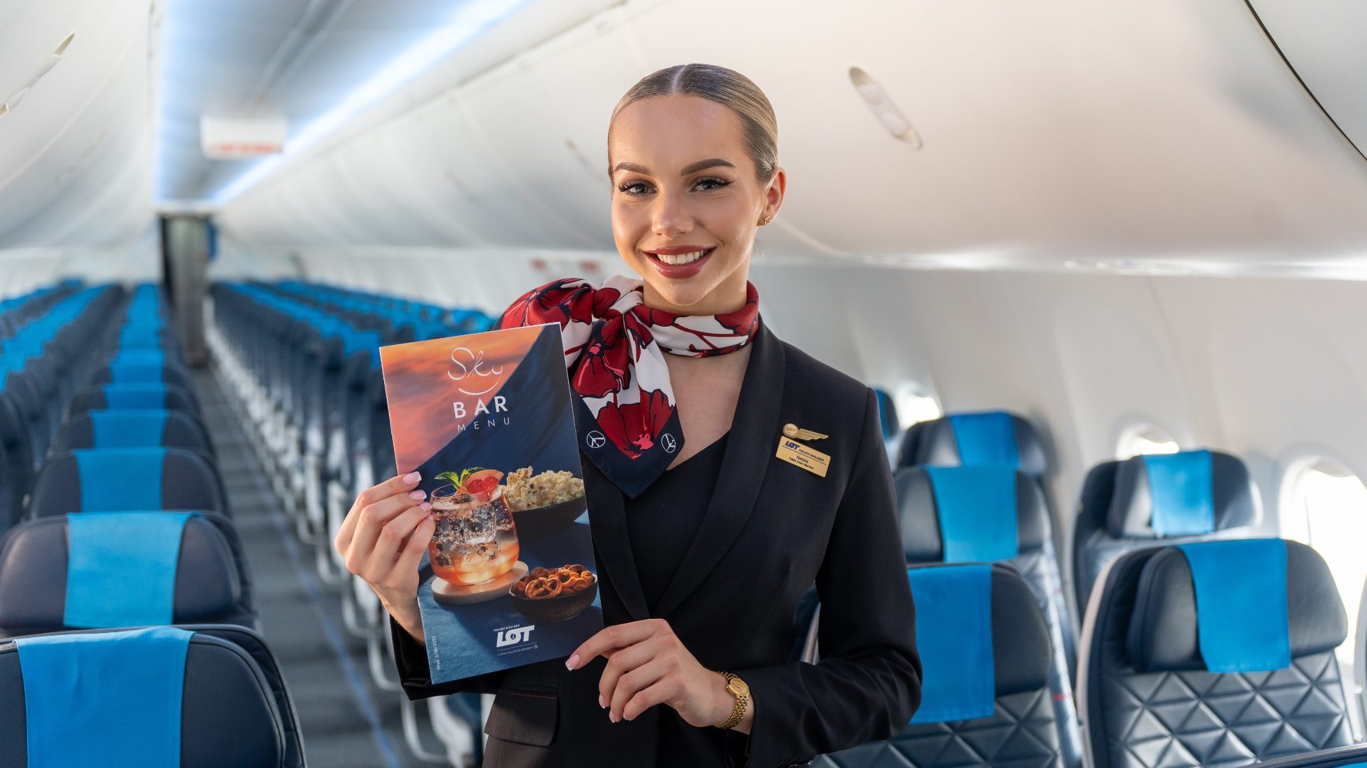 LOT Polish Airlines stewardess on board a Boeing 737 MAX 8 holding a LOT Sky Bar catalog in her hand